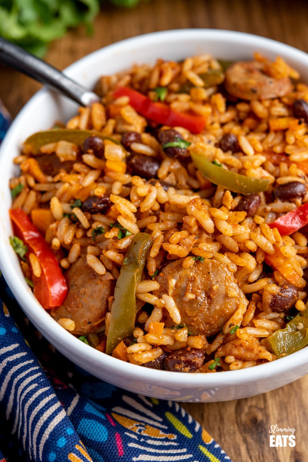 One Pot Cuban Style Rice (with Chicken and Sausage) - this delicious one-pot recipe with spicy seasonings, fresh vegetables and black beans is a perfect meal for any night of the week. Gluten Free, Dairy Free, Slimming Eats and Weight Watchers friendly close up One Pot Cuban Style Rice in white bowl with black handled fork