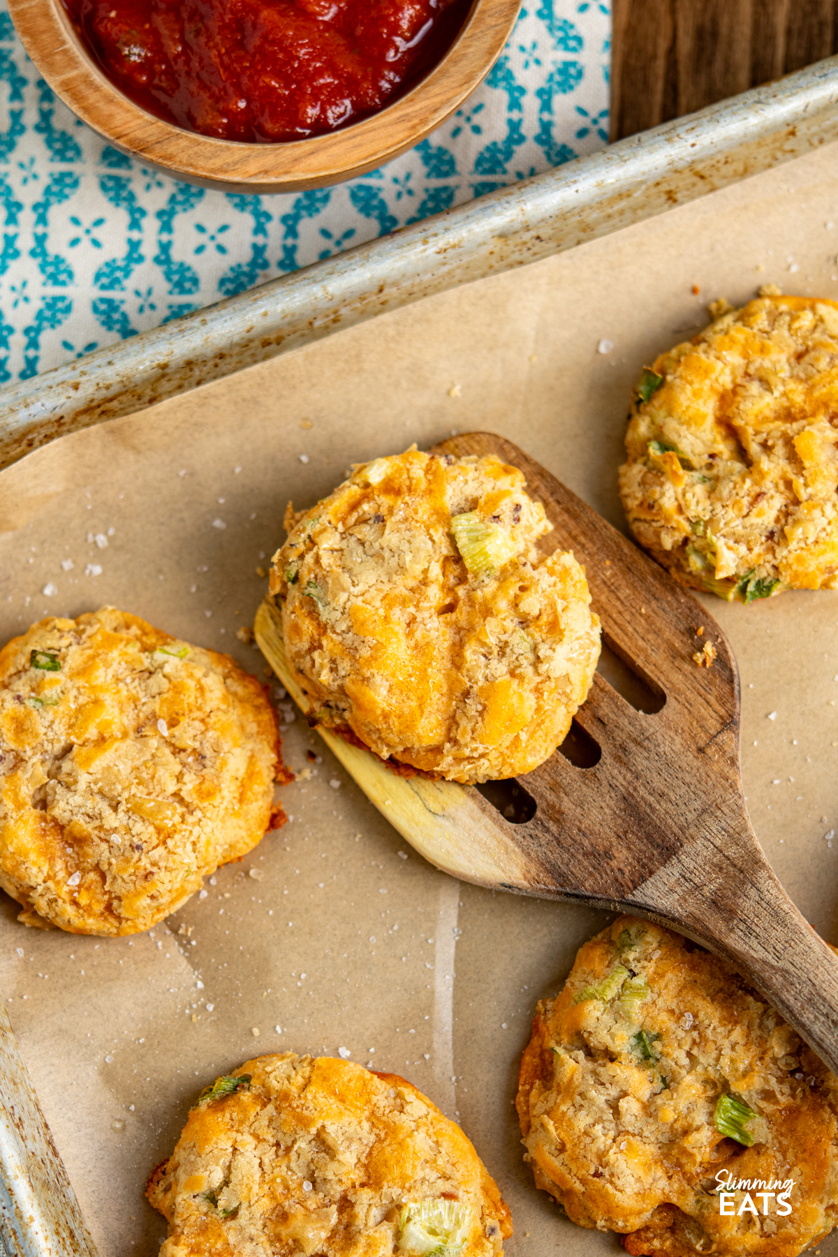 Cheddar Butter Bean Bites on a parchment lined tray with wooden spatula