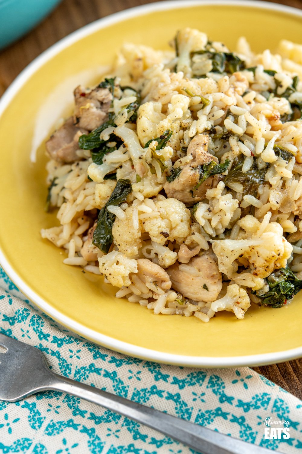 close up of yellow plate of one pot lemon garlic chicken rice with fork to side