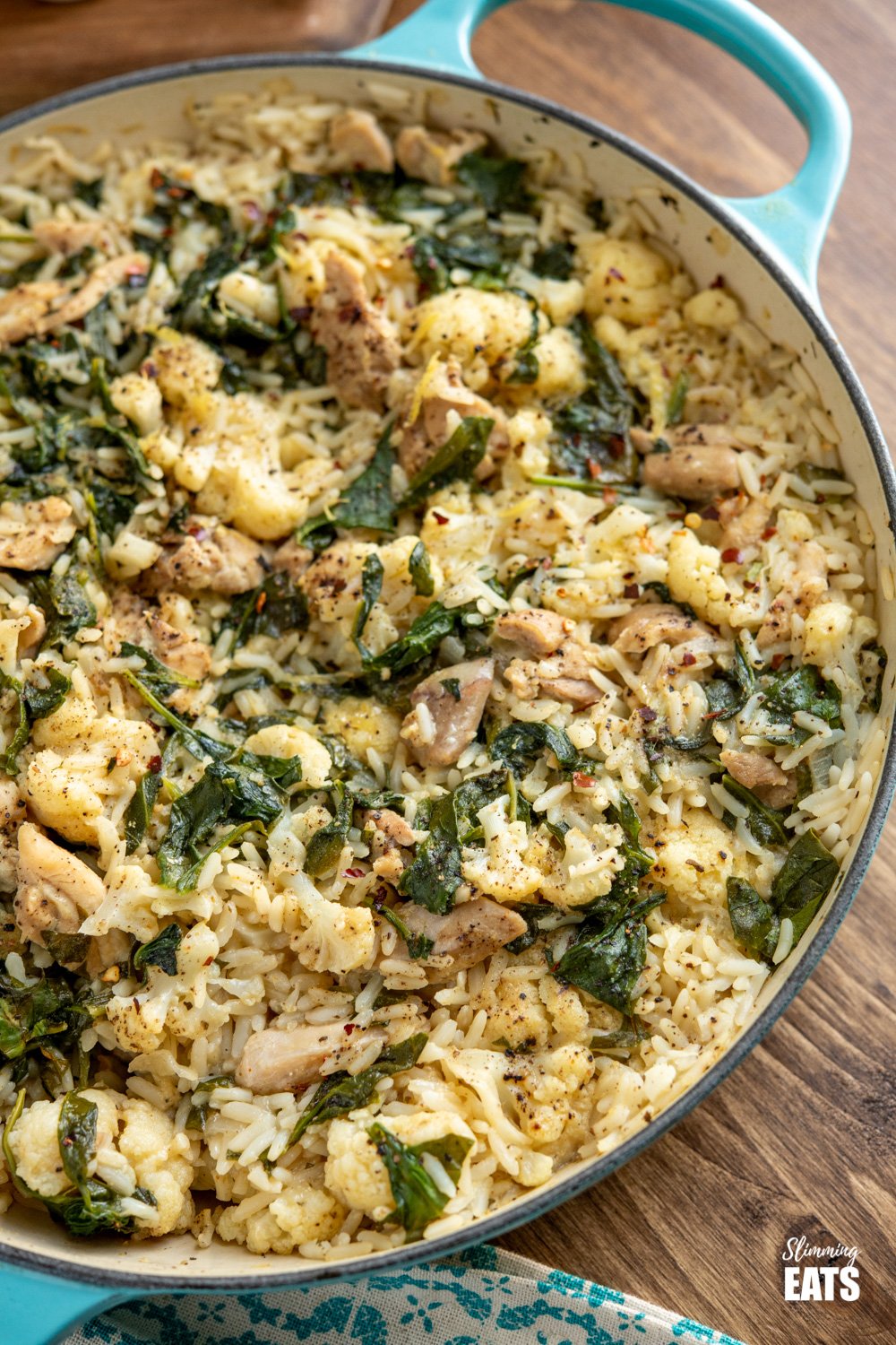 One Pot Lemon Garlic Chicken Rice - a simple all in one pan recipe with the delicious flavours of lemon and garlic and packed with healthy vegetables such as cauliflower and spinach. Dairy free, gluten free. close up of one pot lemon garlic chicken rice in cast iron casserole pan