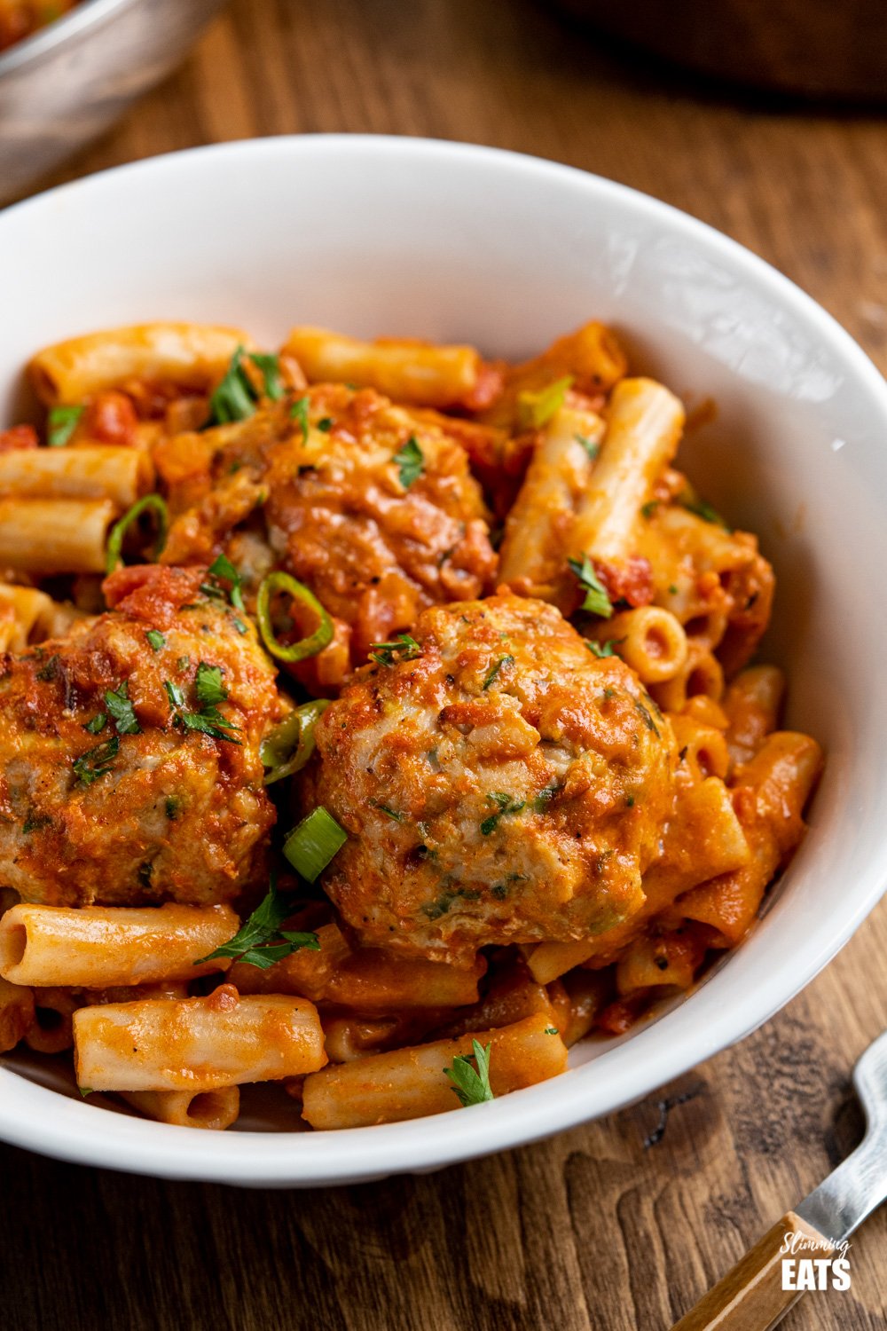 close up of creamy cajun meatballs pasta in white bowl