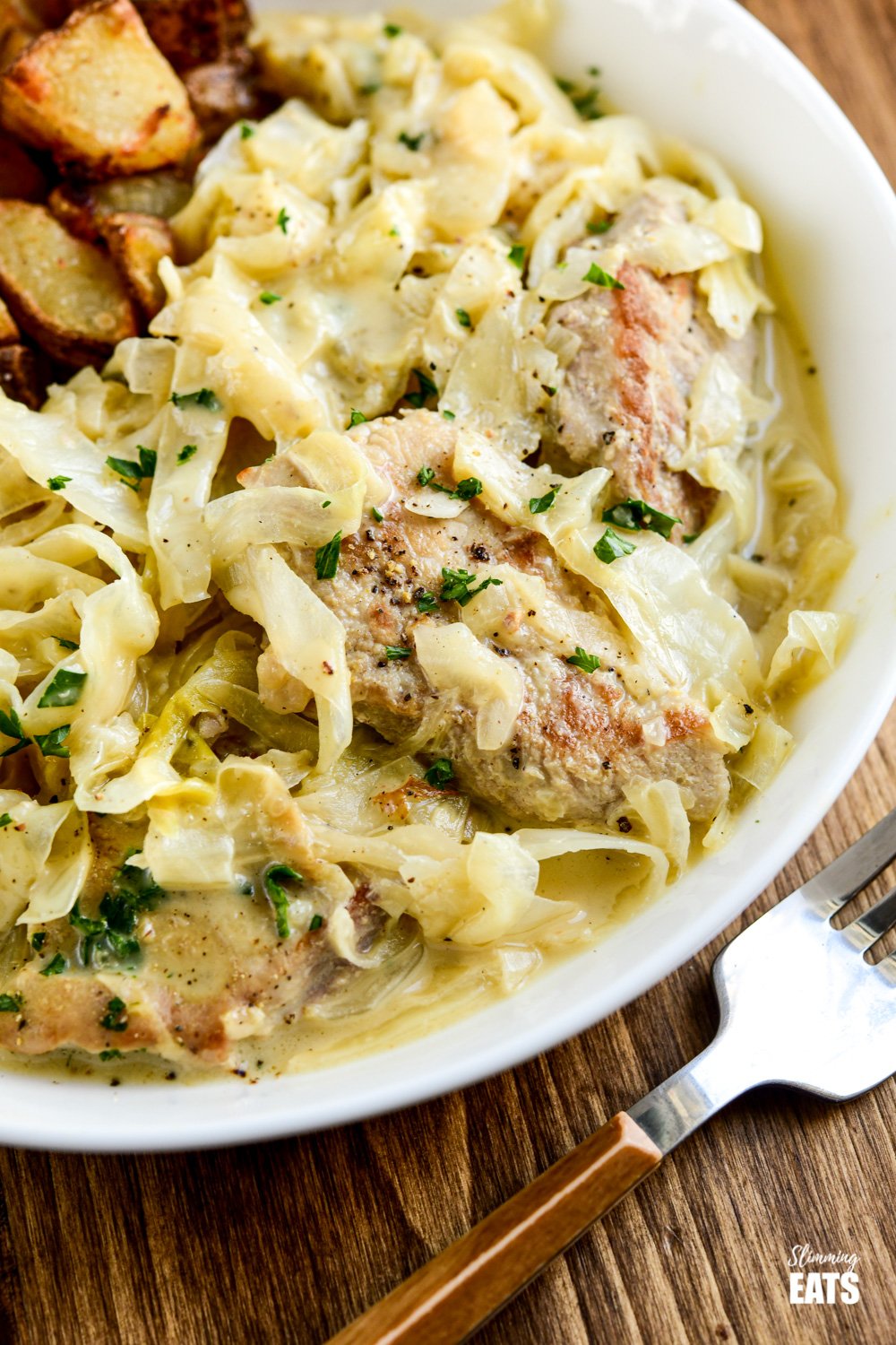 Creamy Garlic Pork with Cabbage - pork pieces in an irresistible lighter creamy garlic sauce with delicious shredded cabbage for a perfect any night of the week dinner. Gluten-Free, Slimming Eats and Weight Watchers friendly close up of creamy garlic pork with cabbage in white dish with fork to side.