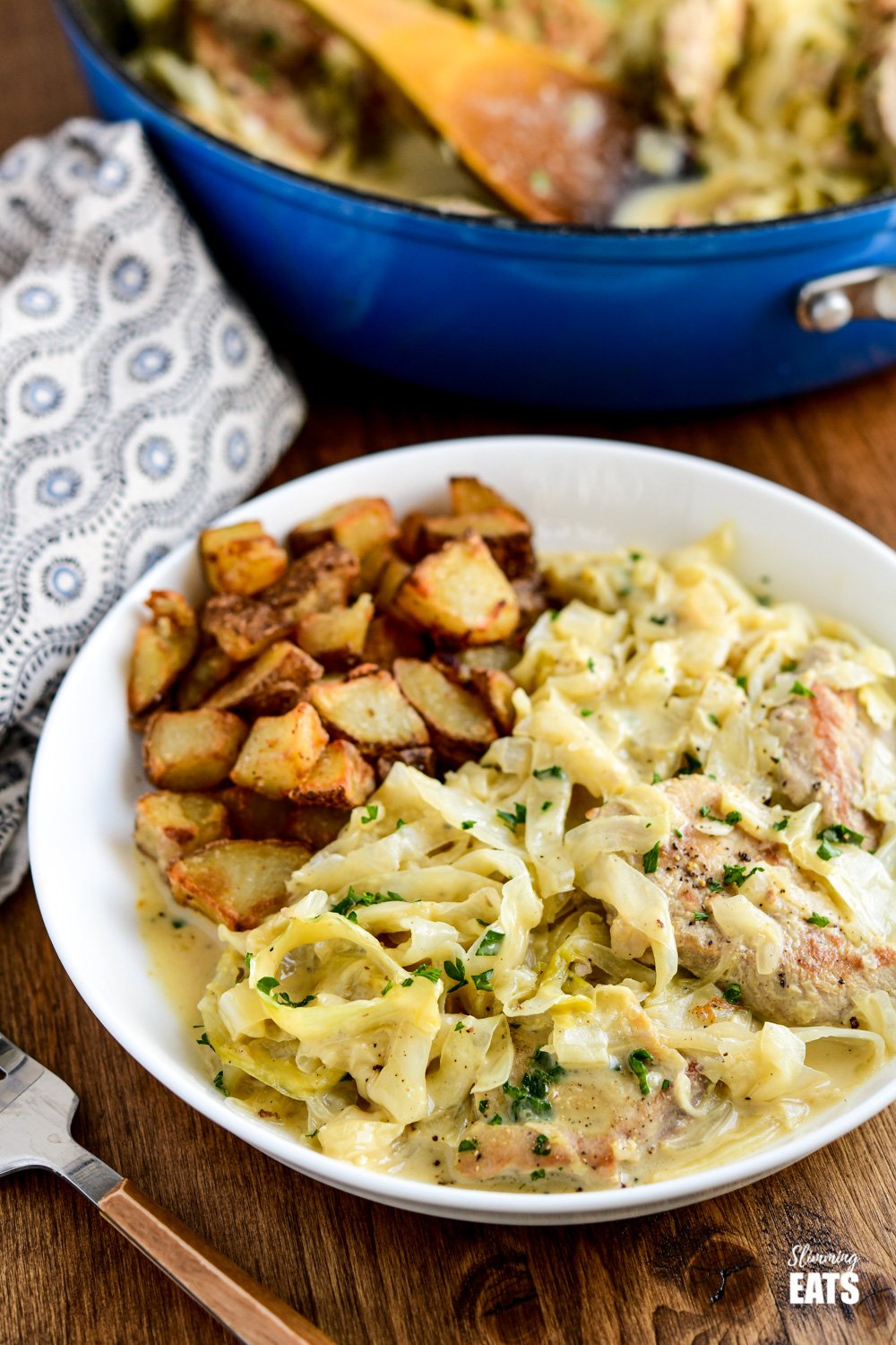 creamy garlic pork with cabbage served in white dish with roasted skinned russet potatoes