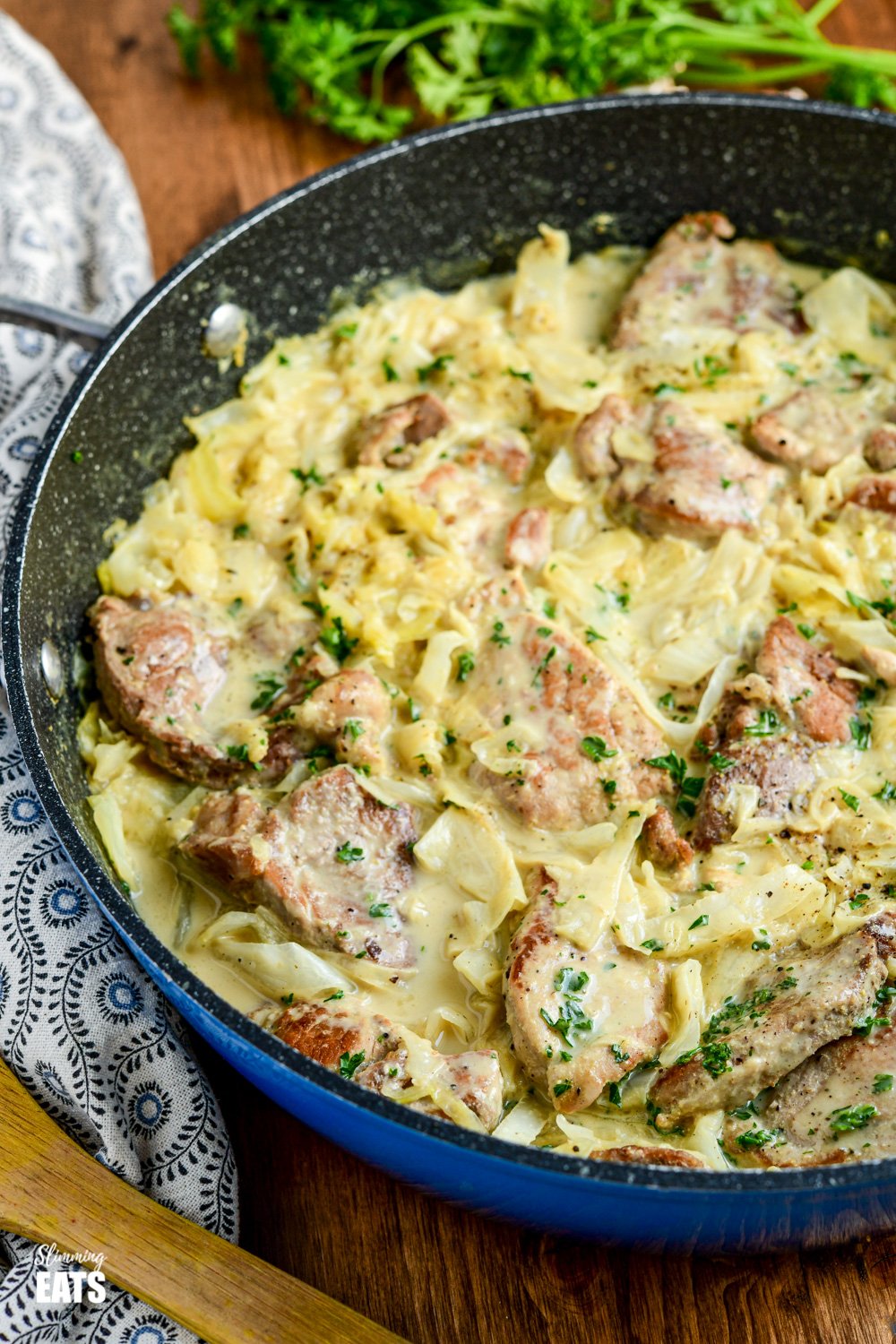 creamy garlic pork with cabbage in frying pan on wooden board
