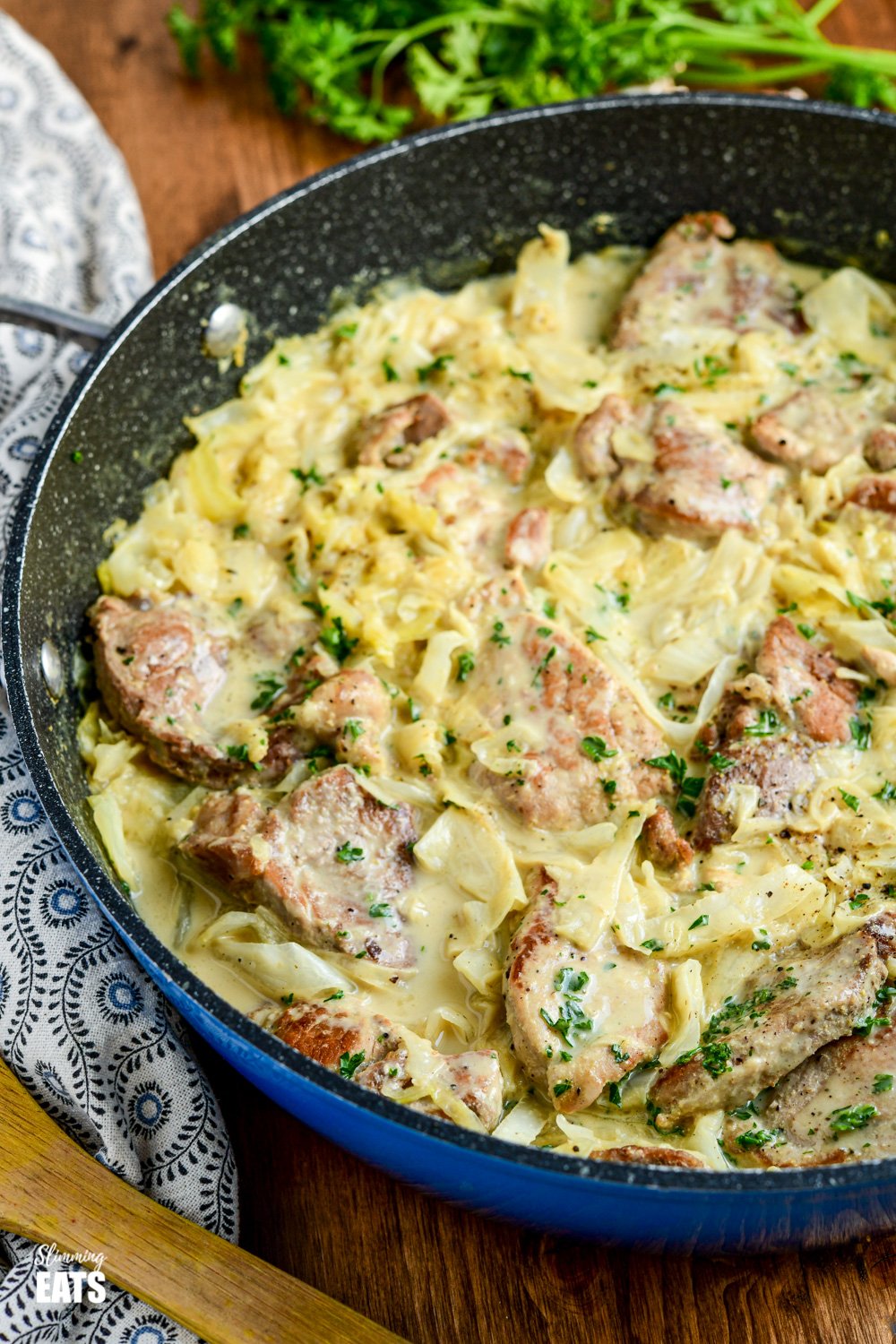 Creamy Garlic Pork with Cabbage - pork pieces in an irresistible lighter creamy garlic sauce with delicious shredded cabbage for a perfect any night of the week dinner. Gluten-Free, Slimming Eats and Weight Watchers friendly creamy garlic pork with cabbage in frying pan on wooden board
