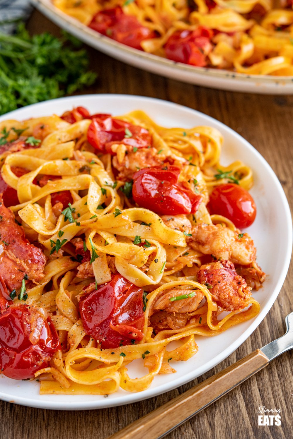 The most amazing fresh Lobster Pasta with the delicious sweet taste of fresh tomatoes and a lemon parsley buttery sauce. et taste of fresh tomatoes and a lemony garlic buttery sauce. Slimming Eats and Weight Watchers friendly close up of serving of lobster pasta on white plate