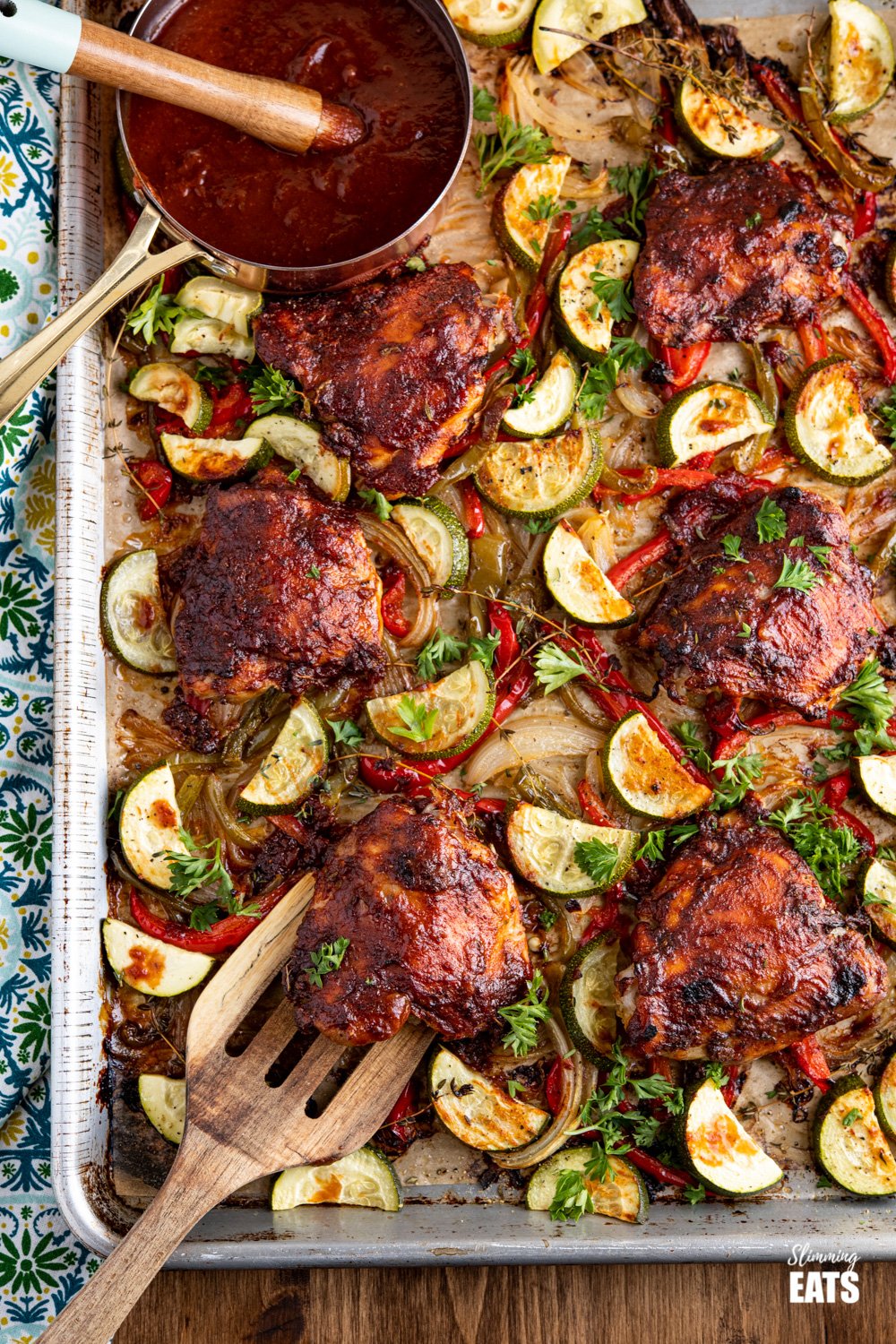 Peach Barbecue Chicken on tray with roasted veggies and small saucepan of peach barbecue sauce with basting brush