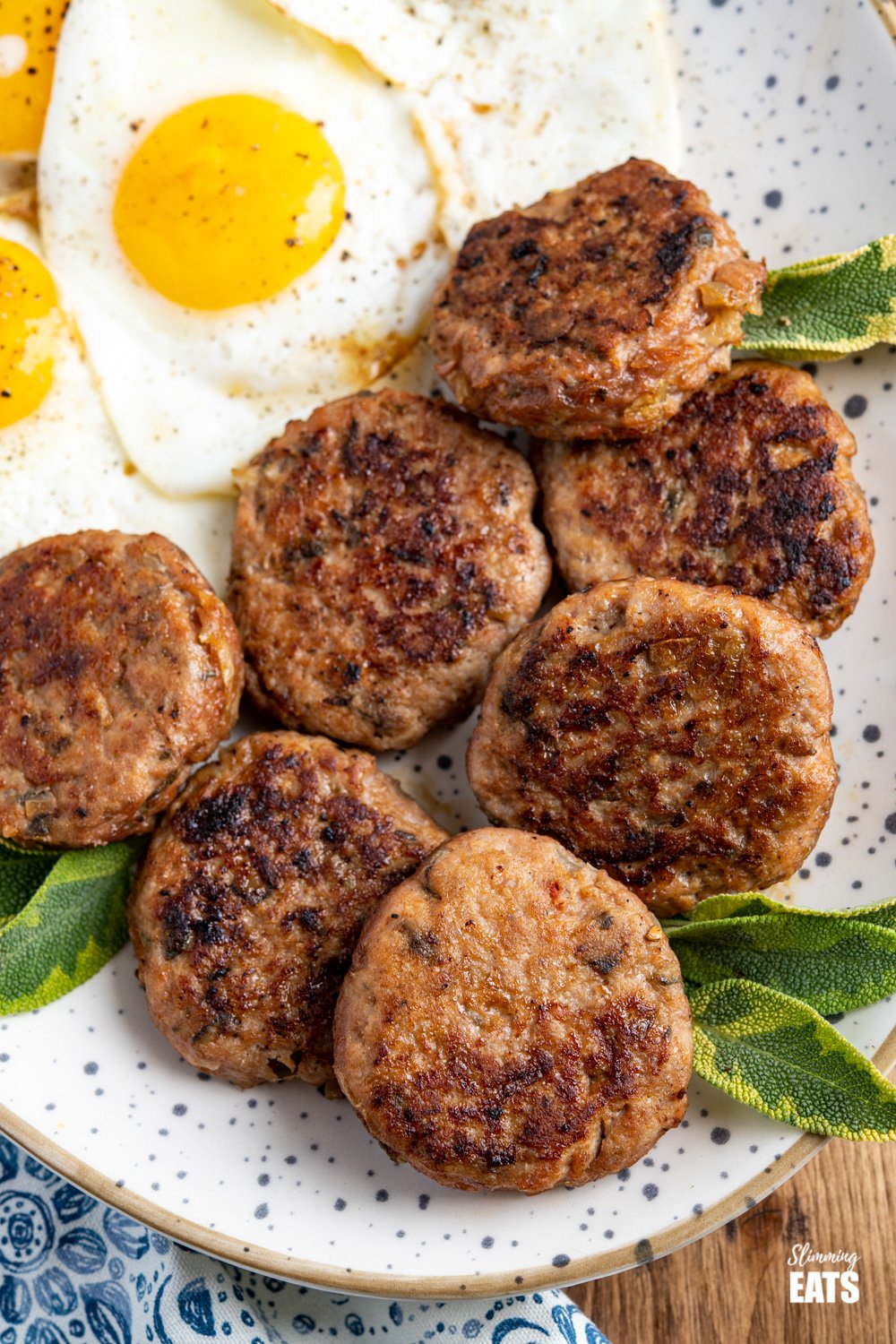 Delicious Homemade Turkey Breakfast Sausage Patties - tasty simple ingredients and the perfect way to start the day with your choice of eggs or other breakfast sides. Gluten free, dairy free, Slimming Eats and Weight Watchers friendly close up of oval speckled plate filled with homemade turkey breakfast sausage patties and fried eggs