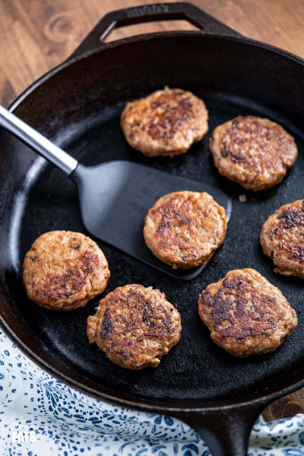 cooked Turkey Breakfast Sausage Patties in a lodge cast iron skillet with spatula