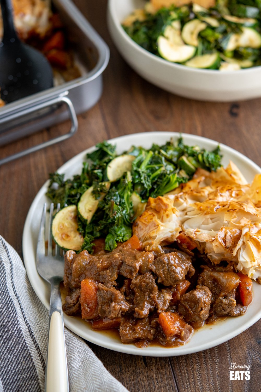 Epic Steak and Vegetable Pie with a delicious golden filo pastry topping - tender pieces of beef with carrots and onion in a deliciously rich homemade gravy. #slimmingeats #weightwatchers #dairyfree #pie #steak #filopastry #beef Steak and Vegetable Pie on plate with zucchini and kale