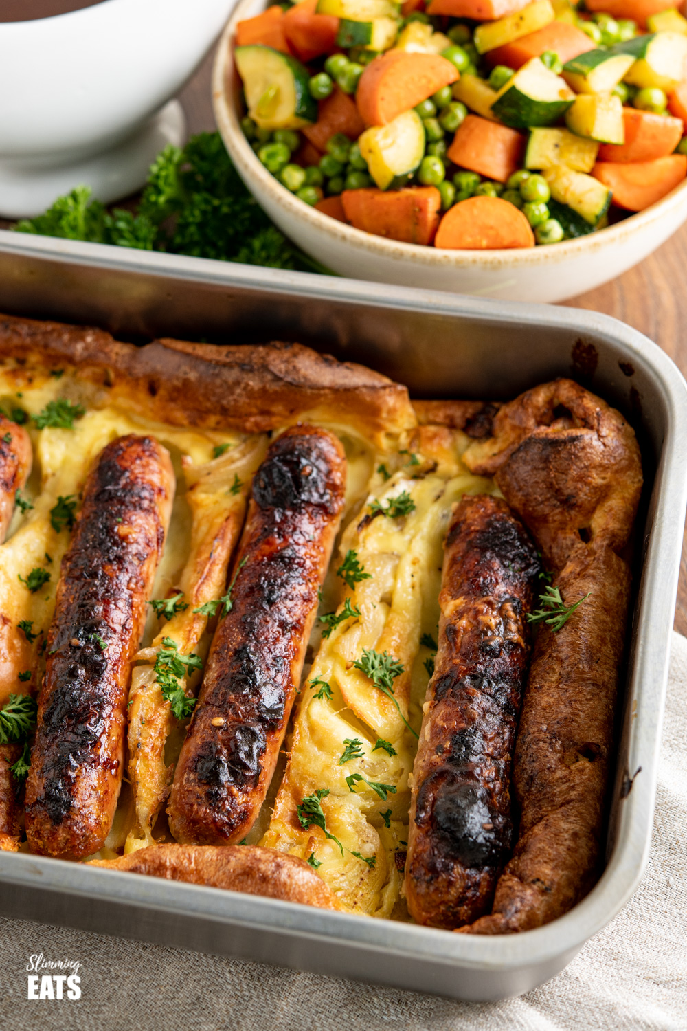 toad in the hole in baking dish with  vegetables in background