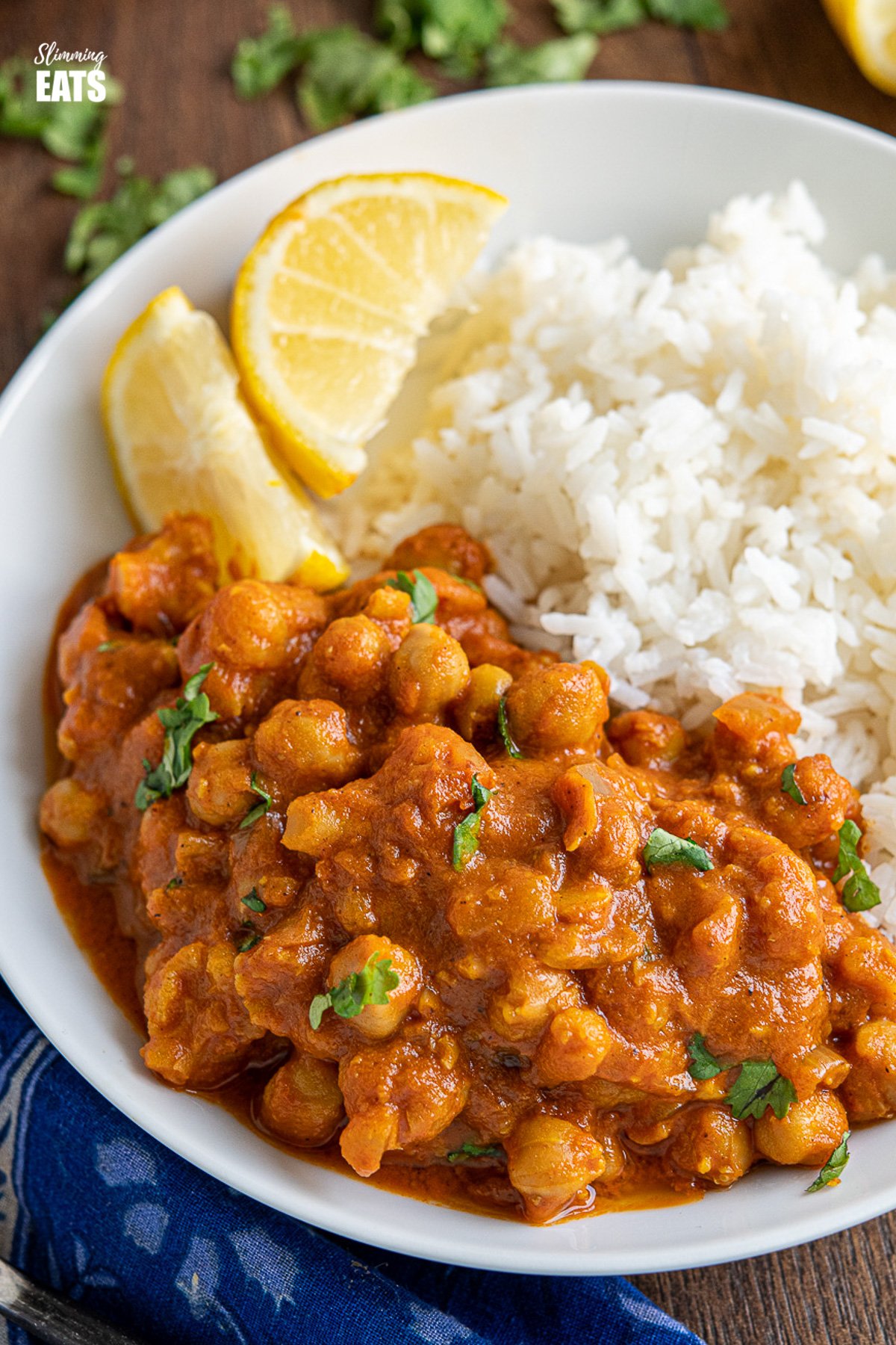 close up of vegan tikka masala in white bowl with rice and lemon wedges