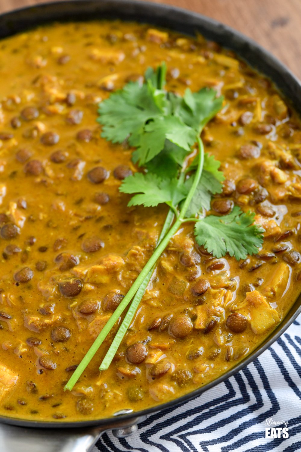 Coconut Chicken and Lentil Curry - rich and creamy easy Coconut Chicken and Lentil Curry using leftover cooked chicken to make this ready and on the table in 40 minutes. #glutenfree #dairyfree #curry #chicken #lentils #slimmingeats #weightwatchers close up of coconut chicken and lentil curry in a frying pan topped with some fresh coriander