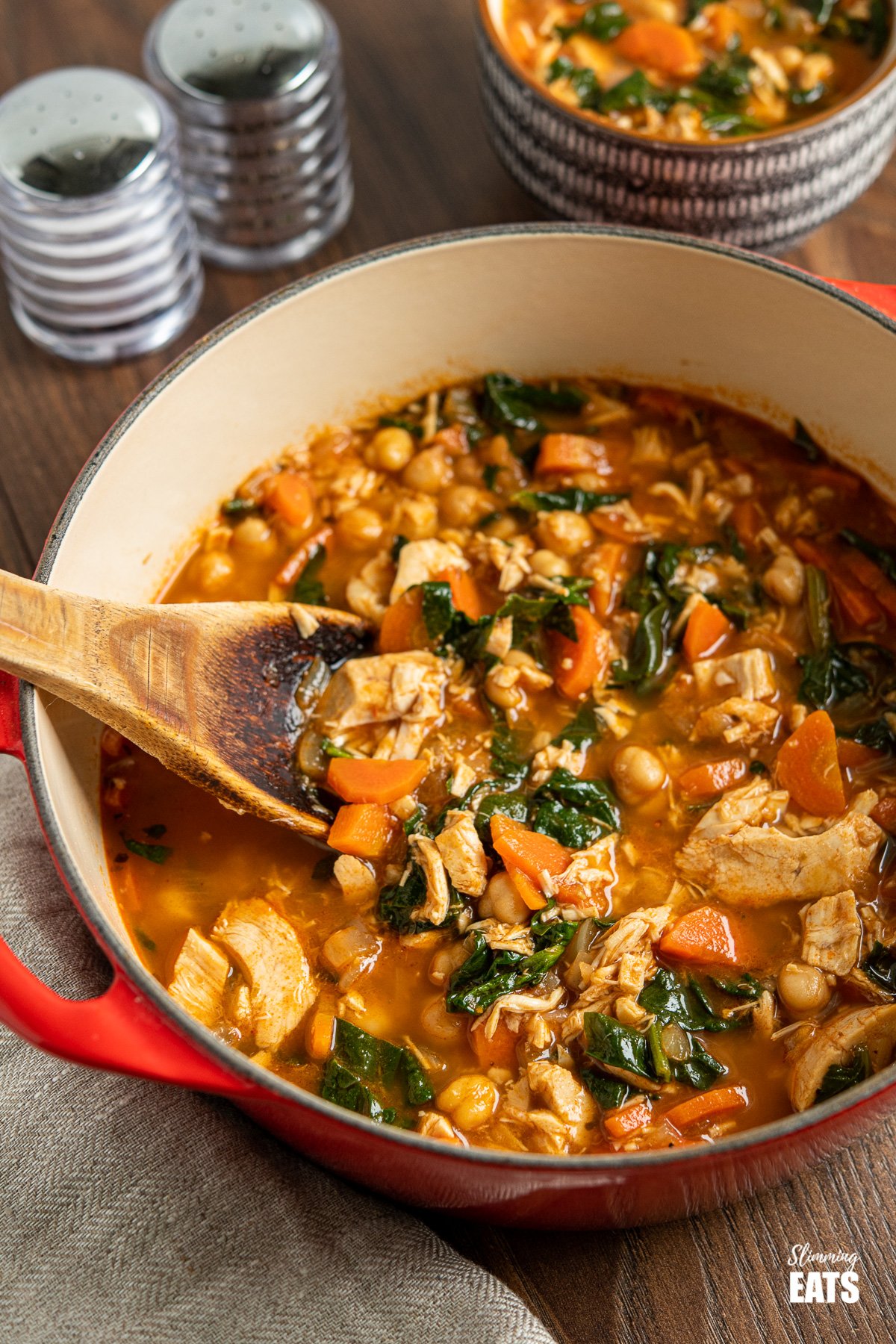 Chicken Chickpea Spinach Soup in red cast iron pot with wooden spoon