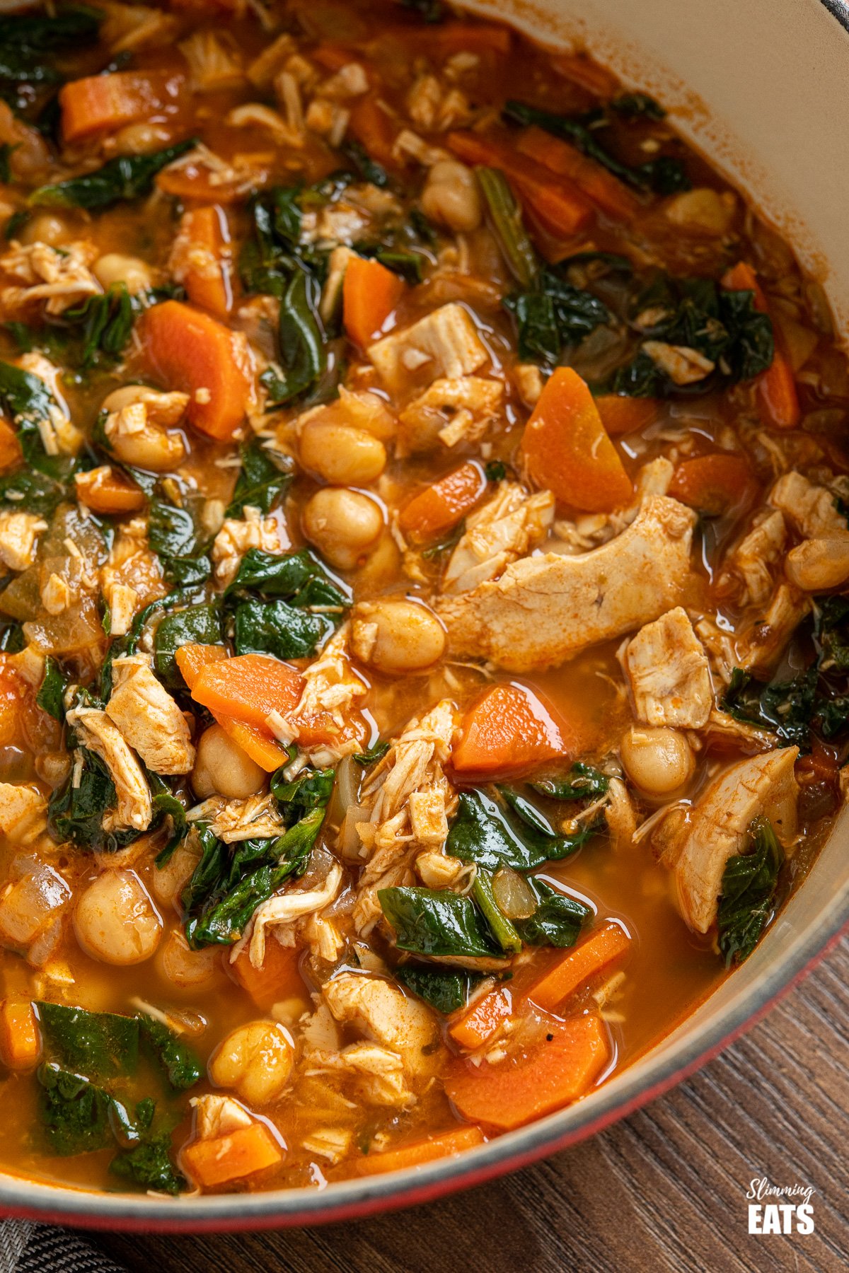 close up of chicken chickpea spinach soup in cast iron pot