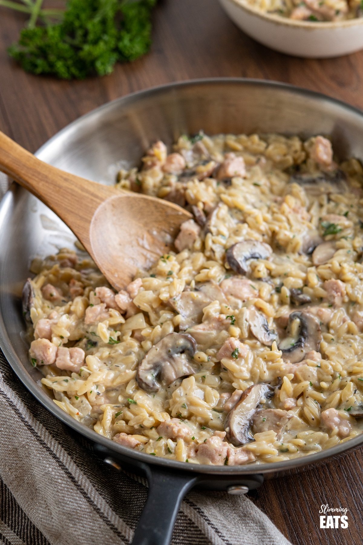 One Pot Creamy Ham Mushroom Orzo (from www.slimmingeats.com) - a delicious creamy orzo dish, with tender pieces of ham and flavoursome mushrooms, for an easy meal that is ready and on the table in less than 30 minutes. #orzo #onepot #ham #creamy #Mushrooms #slimmingworld #weightwatchers creamy orzo in frying pan with wooden spoon