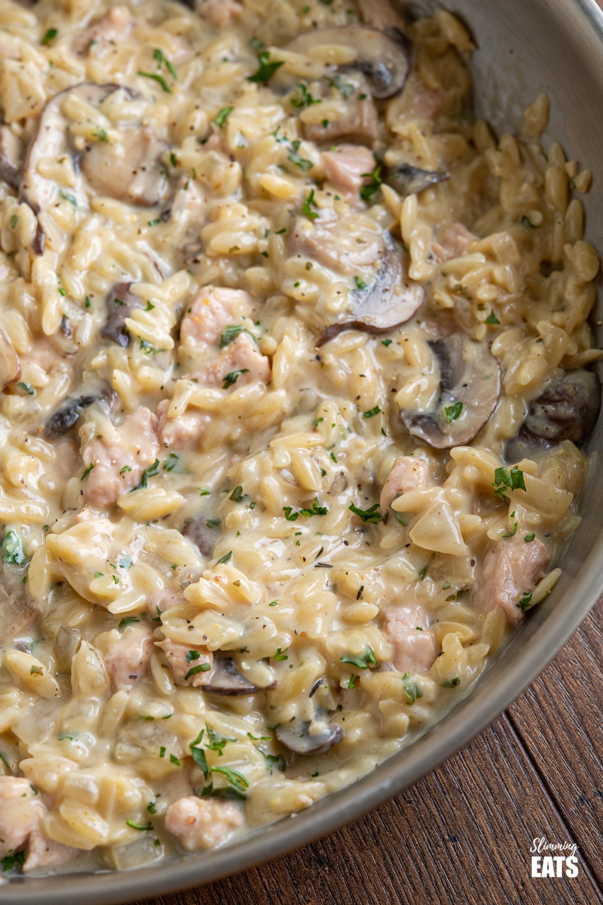 close up of creamy ham and mushroom orzo in frying pan