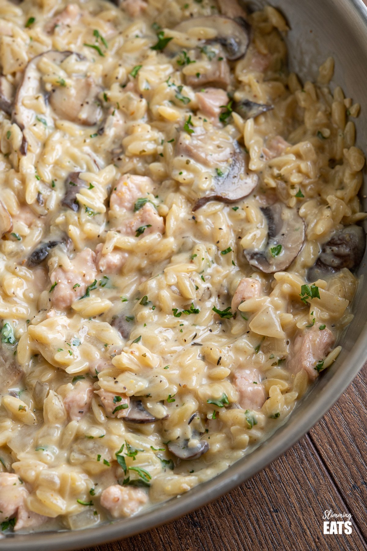 One Pot Creamy Ham Mushroom Orzo (from www.slimmingeats.com) - a delicious creamy orzo dish, with tender pieces of ham and flavoursome mushrooms, for an easy meal that is ready and on the table in less than 30 minutes. #orzo #onepot #ham #creamy #Mushrooms #slimmingworld #weightwatchers close up of creamy ham and mushroom orzo in frying pan