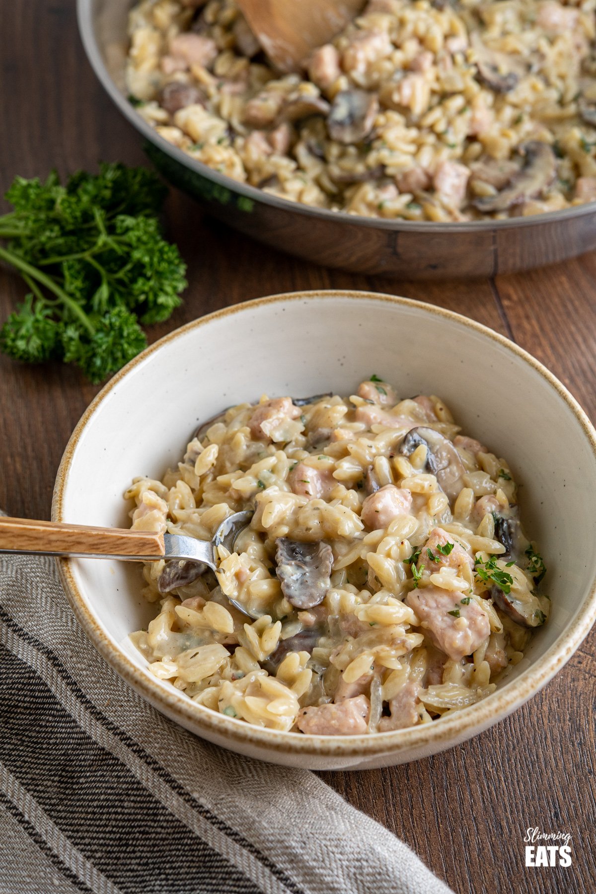 creamy ham and mushroom orzo in a white bowl