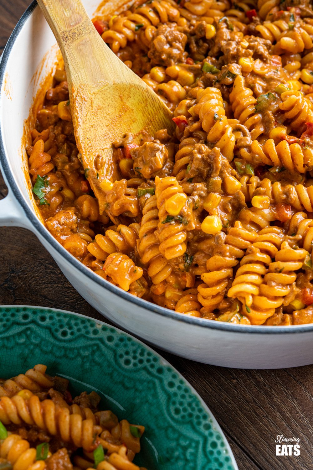 One Pot Taco Beef Pasta - an easy yummy recipe that is cooked all in one pan. Cheesy spicy taco flavoured deliciousness!! #slimmingeats #weightwatchers #onepot #beef #pasta #taco close up of One Pot Taco Beef Pasta in skillet with wooden spoon
