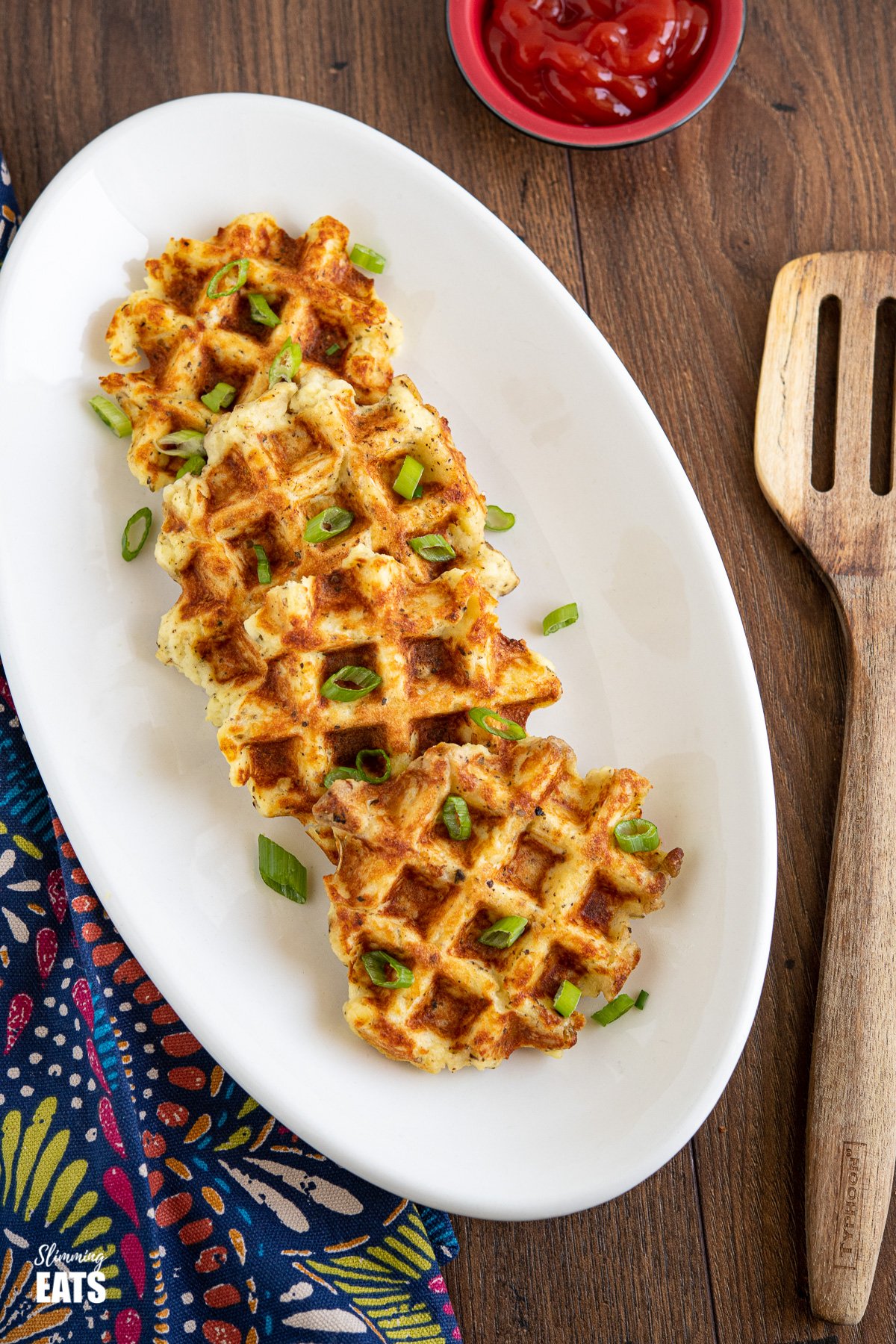 Leftover Mash Potato Waffles on white oval plate with ketchup and wooden spatula