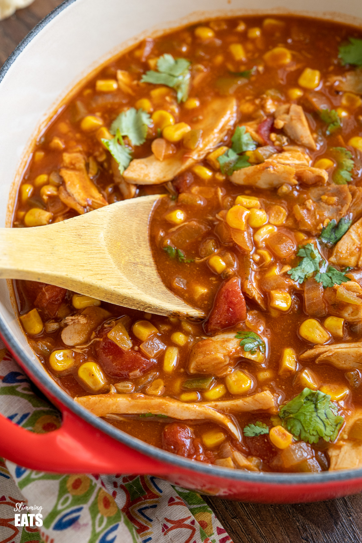 close up of Easy Chicken Tortilla Soup in cerise cast iron pot with wooden spoon