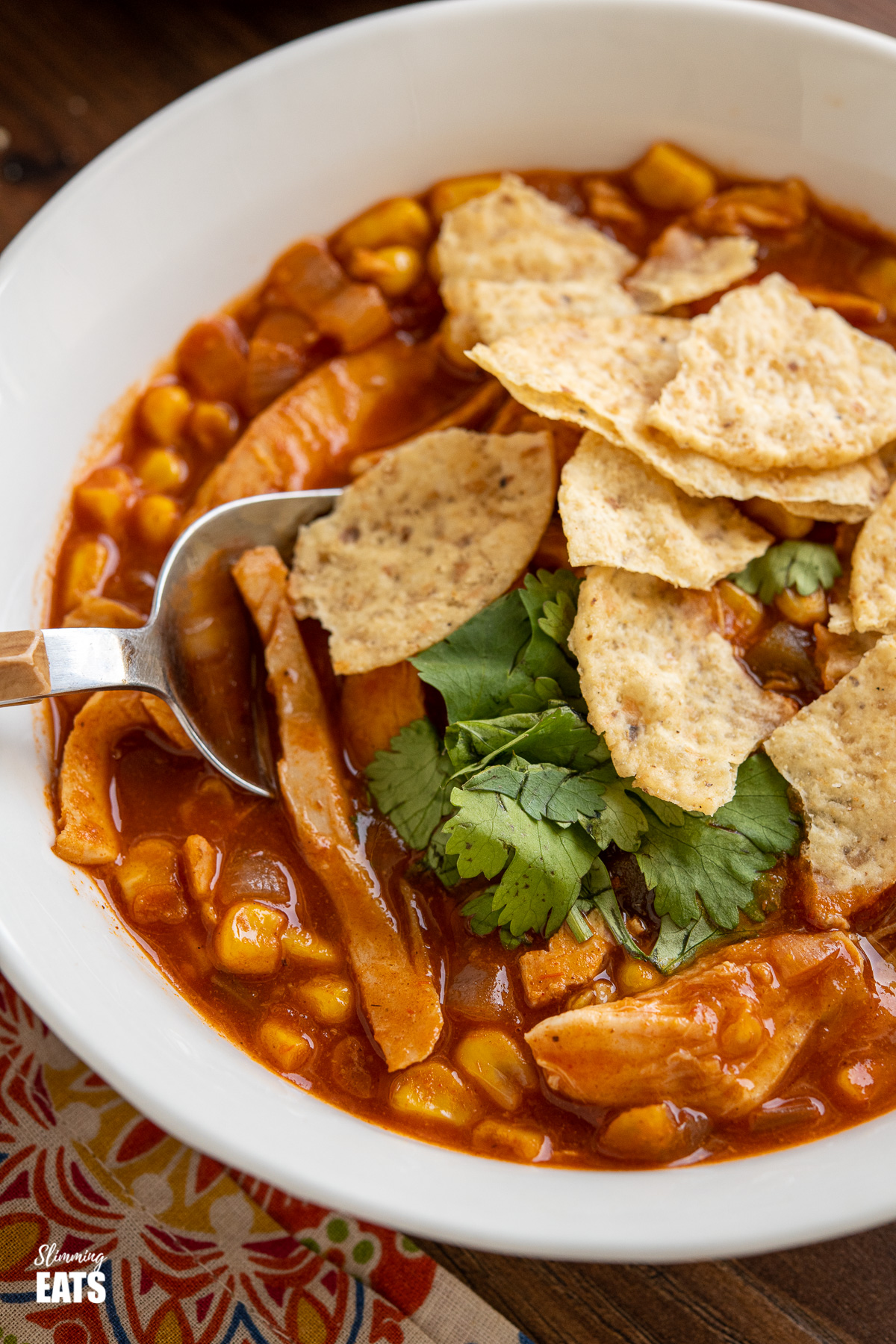 close up of white bowl of Easy Chicken Tortilla Soup with crushed tortilla chips