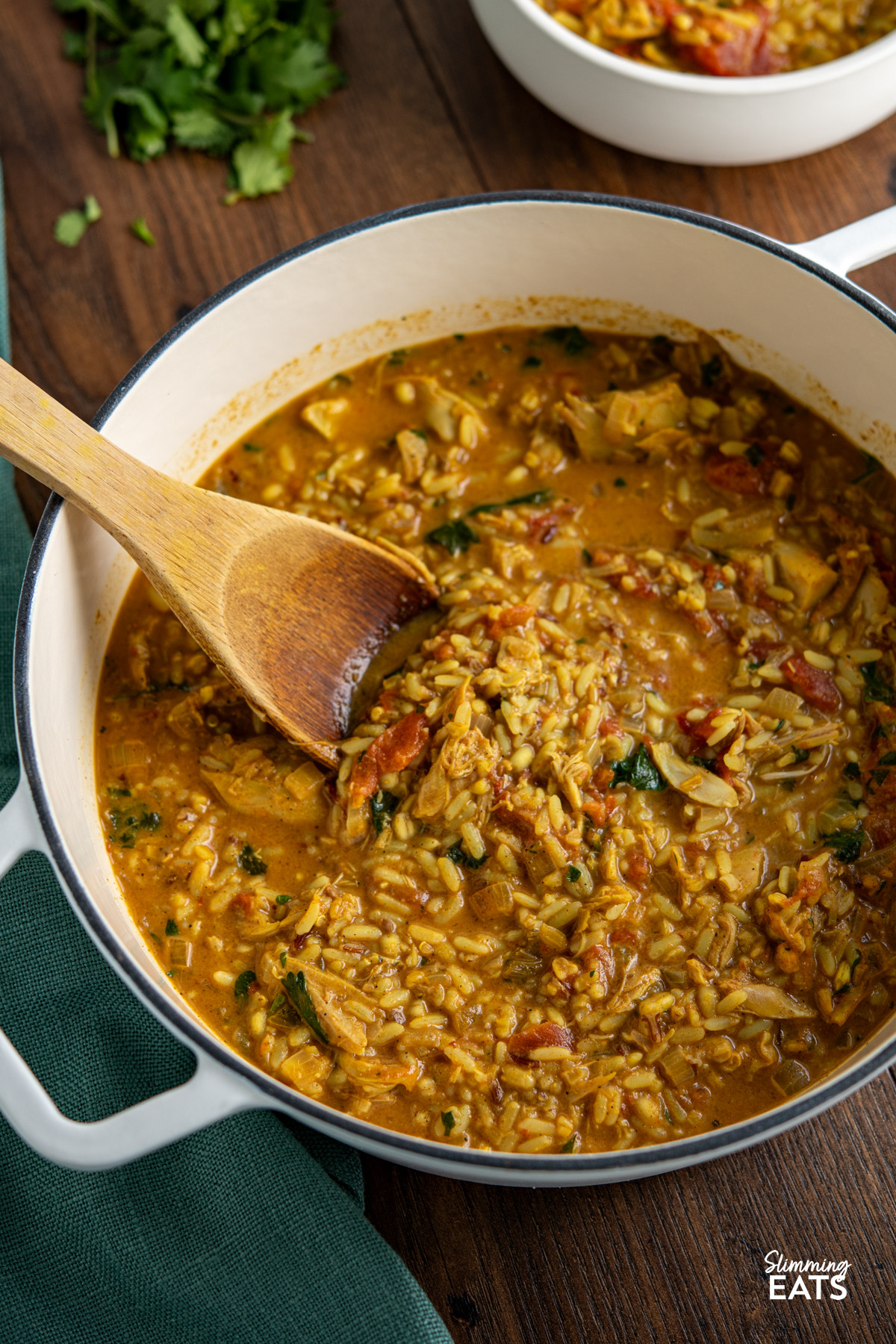 Coconut Chicken Rice Soup (from www.slimmingeats.com) - an easy to make filling bowl of soup that comes packed with flavour. You'll want to make this every week. #slimmingeats #weightwatchers #glutenfree #dairyfree #soup #chicken #rice Coconut Chicken Rice Soup in white cast iron pot with wooden spoon