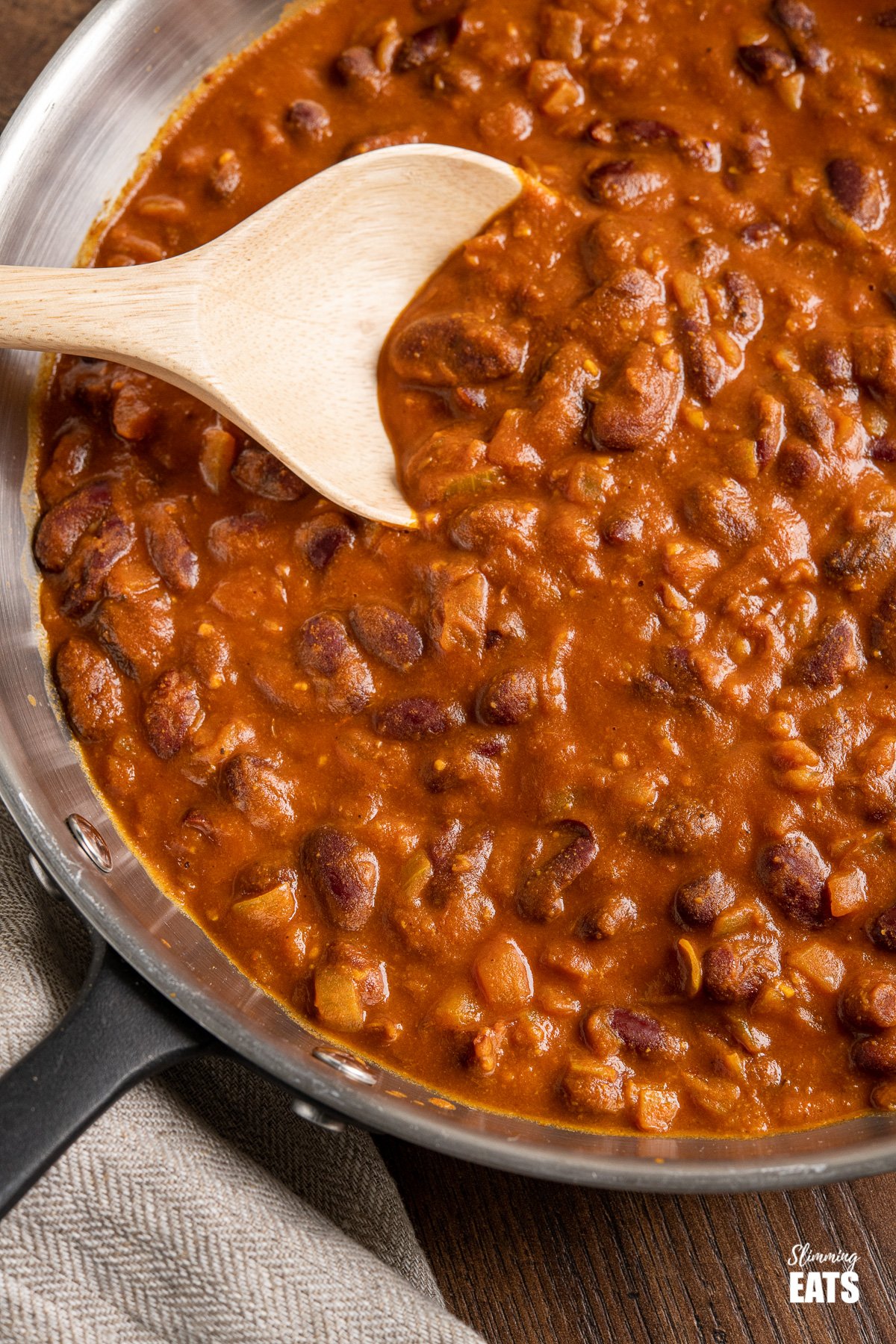 Kidney Bean Curry (Rajma) from www.slimmingeats.com - a delicious vegetarian curry made with Red Kidney Beans, onions, tomato (passata) and a blend of spices. #bean #curry #slimmingeats #weightwatchers #vegetarian #Indian close up of Kidney Bean Curry (Rajma) in frying pan with wooden spoon