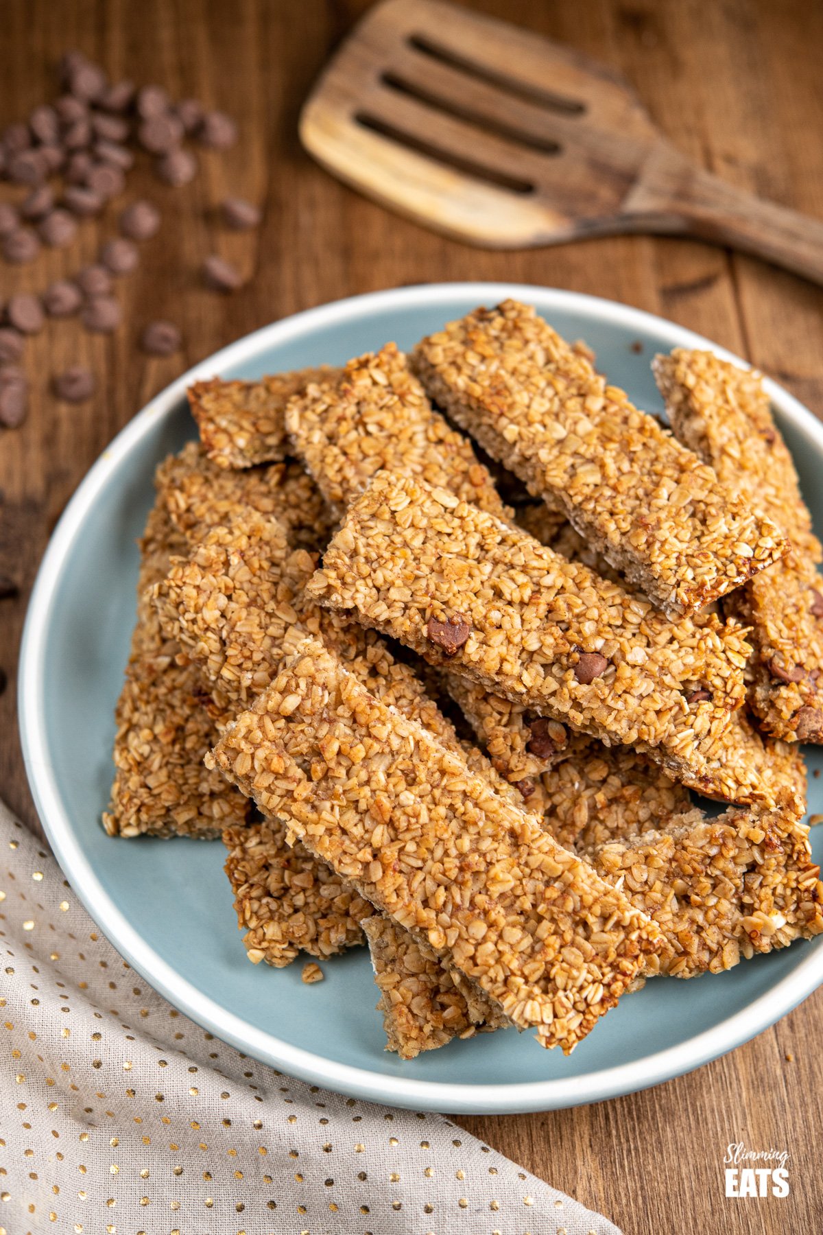 Healthy Chocolate Chip Banana Granola Bars on a blue grey plate with scattered chocolate chips