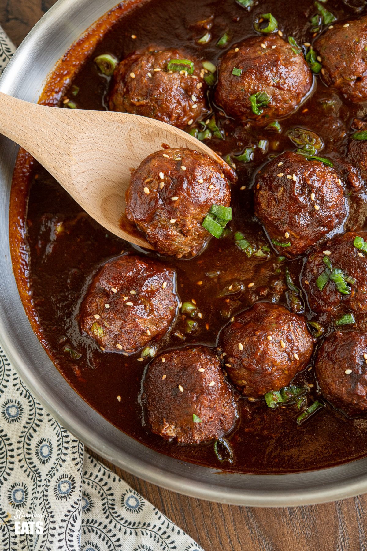 Saucy Asian Hidden Vegetable Beef Meatballs - you will love these tender juicy meatballs with hidden vegetables in a flavour-packed sauce. Gluten Free, Dairy Free, Slimming Eats and Weight Watcher friendly close up of Saucy Asian Hidden Vegetable Beef Meatballs in frying pan with wooden spoon