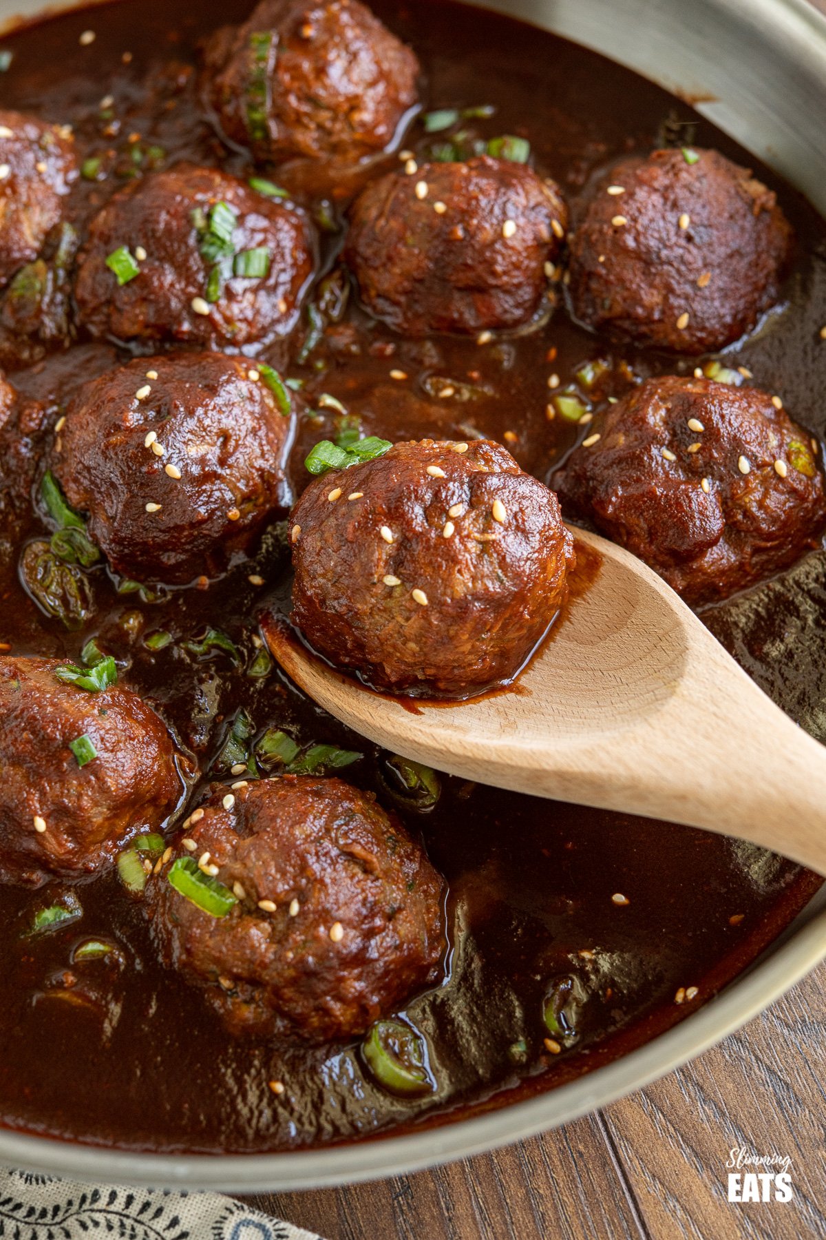 Saucy Asian Hidden Vegetable Beef Meatballs - you will love these tender juicy meatballs with hidden vegetables in a flavour-packed sauce. Gluten Free, Dairy Free, Slimming Eats and Weight Watcher friendly close up of Saucy Asian Hidden Vegetable Beef Meatball on wooden spoon in frying pan