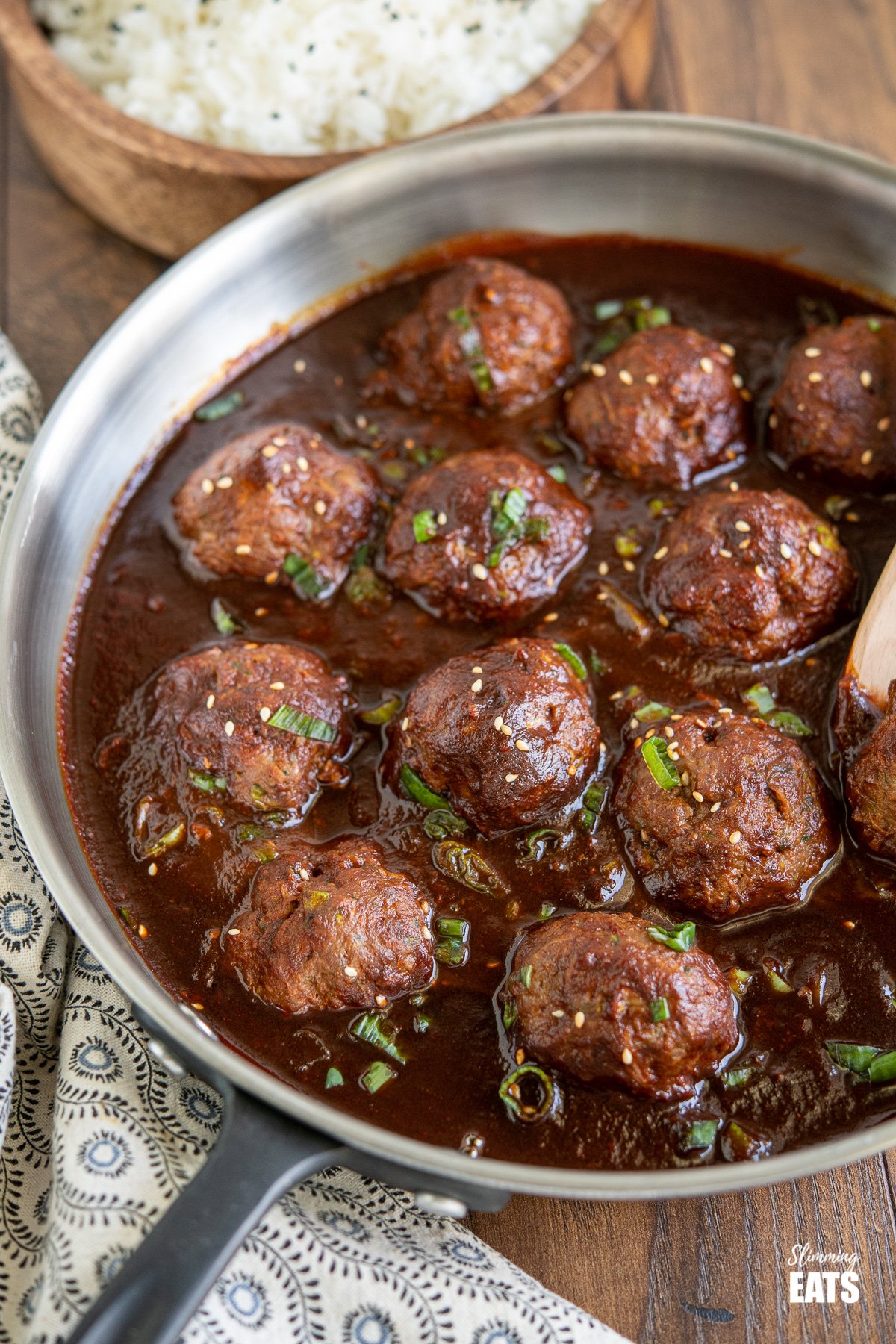 Saucy Asian Hidden Vegetable Beef Meatballs - you will love these tender juicy meatballs with hidden vegetables in a flavour-packed sauce. Gluten Free, Dairy Free, Slimming Eats and Weight Watcher friendly Saucy Asian Hidden Vegetable Beef Meatballs in frying pan with wooden bowl of rice in background