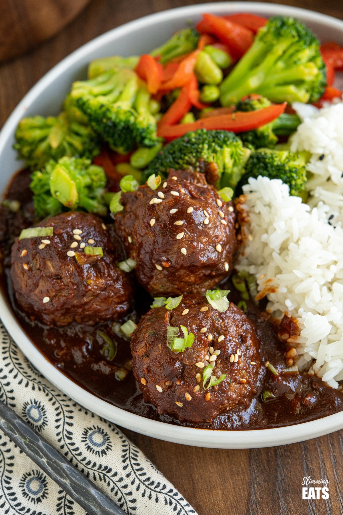 close up of Saucy Asian Hidden Vegetable Beef Meatballs on grey plate with rice and vegetables