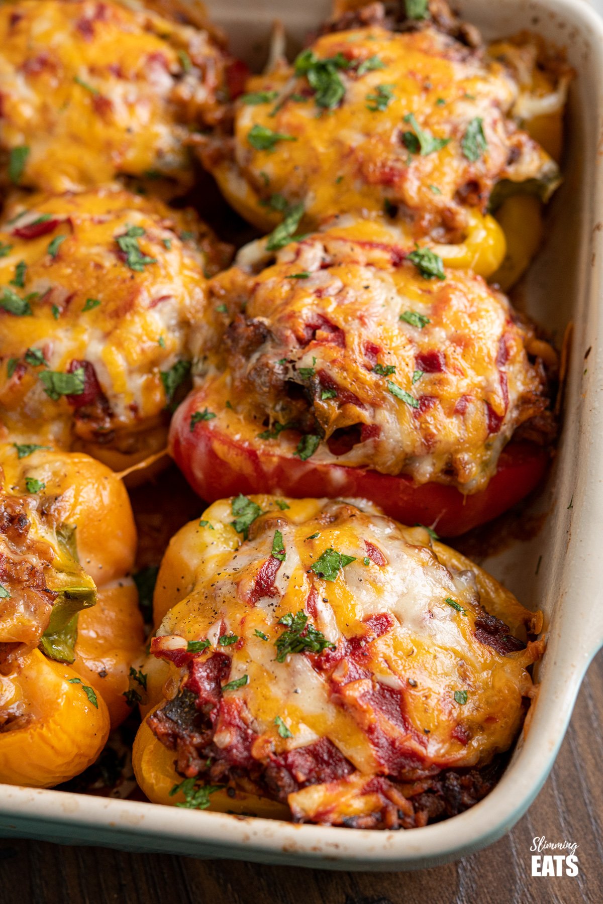 close up of Stuffed Peppers in a baking dish topped with melted cheese and chopped parsley
