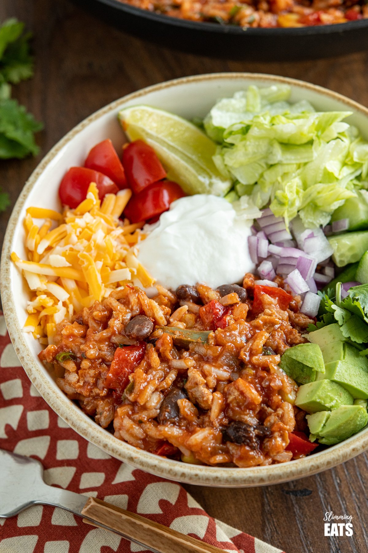 close up of turkey rice burrito bowls with toppings on wooden board