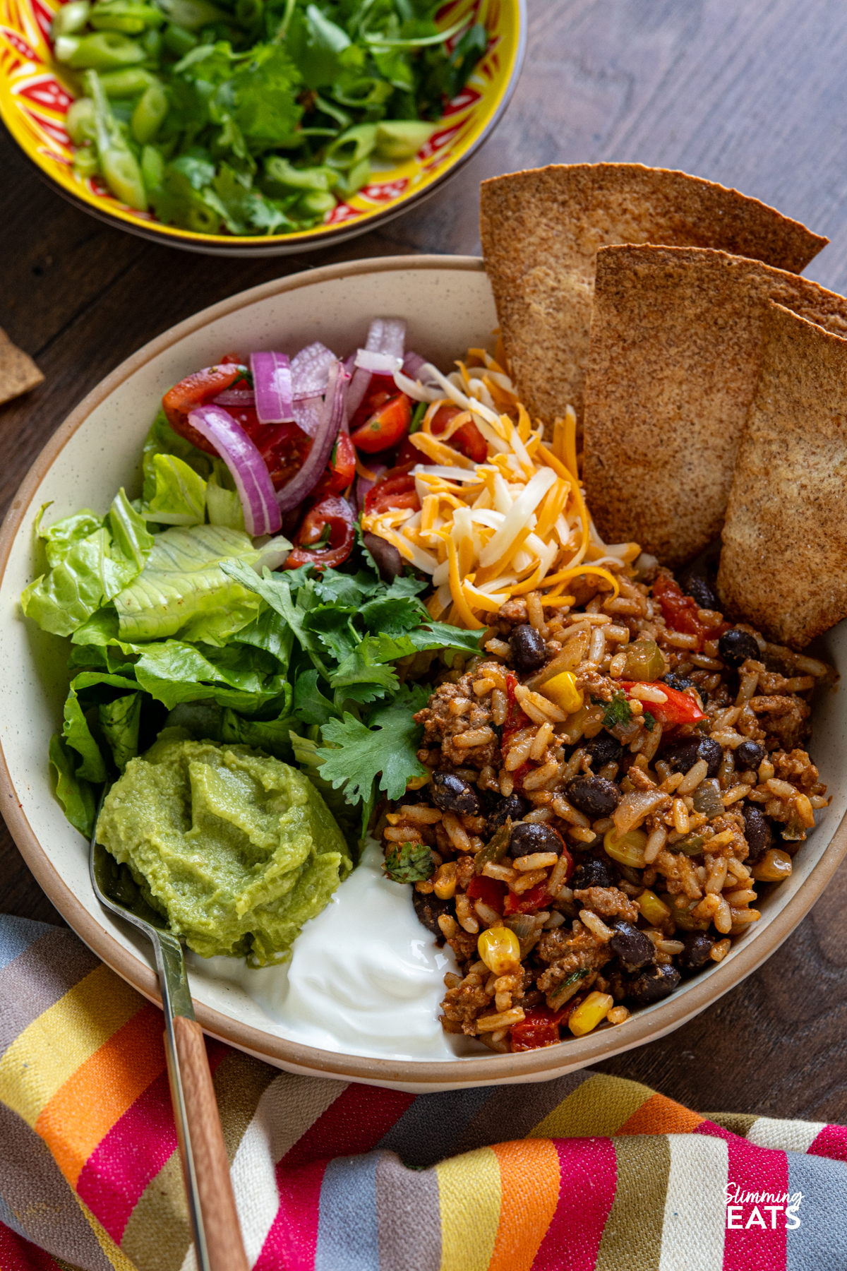 These Turkey Rice Burrito Bowls make a great family meal - sit down and grab a bowl with your favourite toppings. Gluten free, dairy free, Slimming Eats and Weight Watchers friendly Turkey Burrito Rice bowl with lettuce colby jack cheese, guacamole, soured cream and crispy oven baked whole meal tortillas