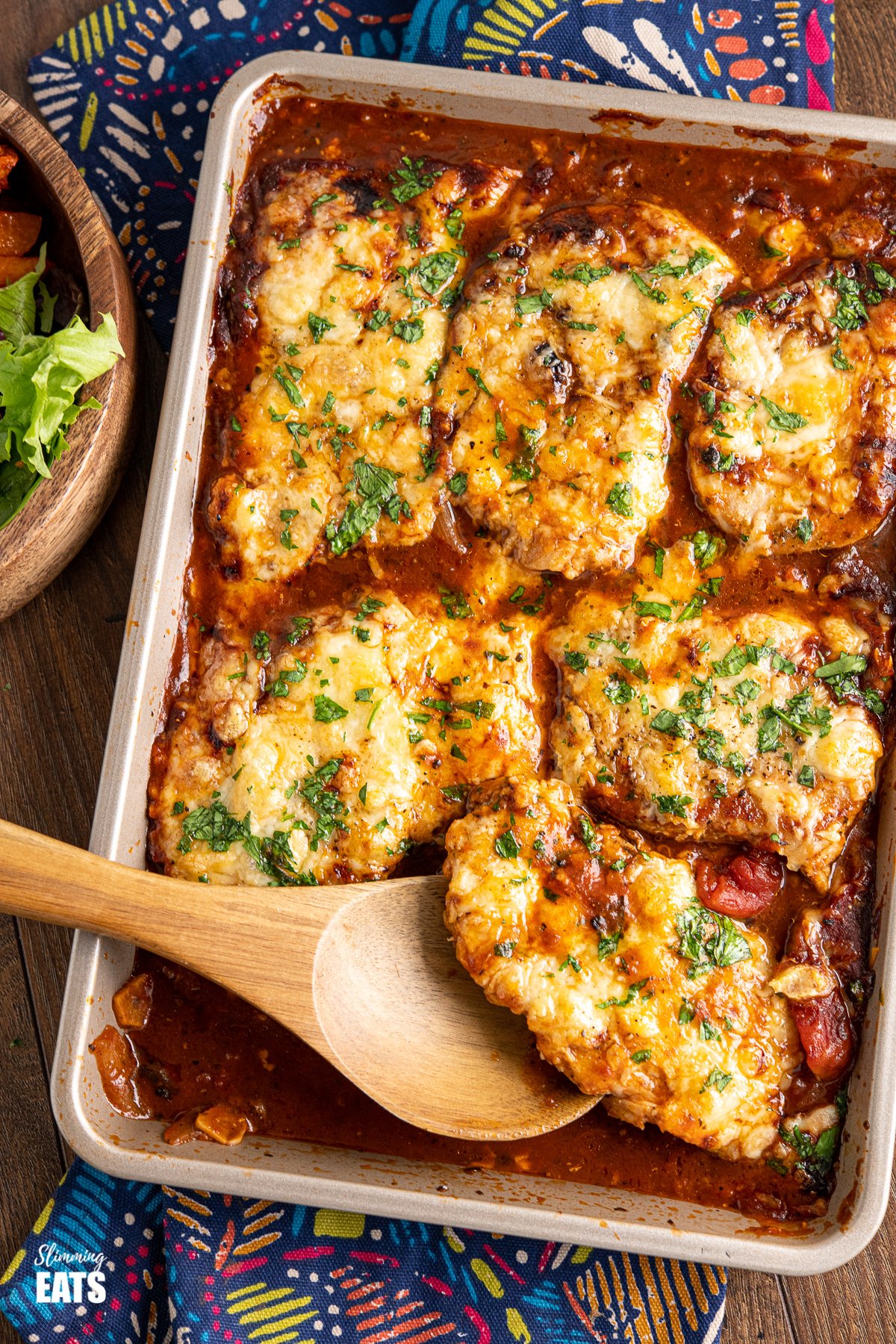 Cheesy Topped Mediterranean Pork Loin Chops on baking tray with wooden spoon