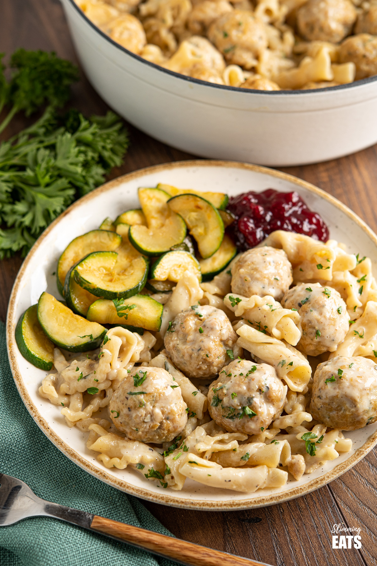 white plate with golden yellow rim dished up with One Pot Turkey Swedish Meatball Pasta sauteed zucchini and lingonberry sauce