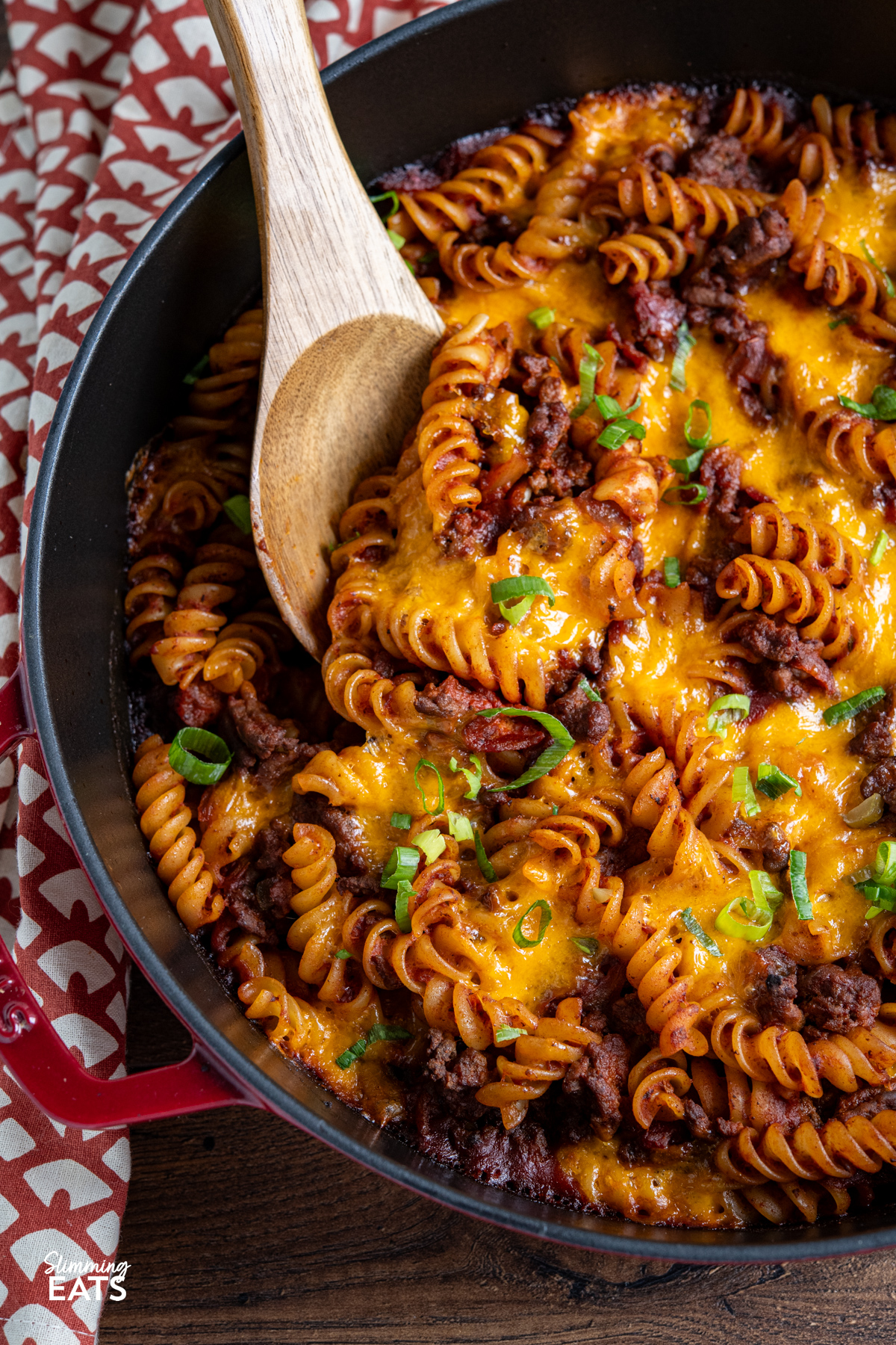 This BBQ Bacon Cheeseburger Pasta Bake is a hearty, flavour-packed family dinner with all the best cheeseburger flavours combined in one cheesy, comforting pasta dish. close up of BBQ Bacon Cheeseburger Pasta Bake in cherry cast iron staub skillet,