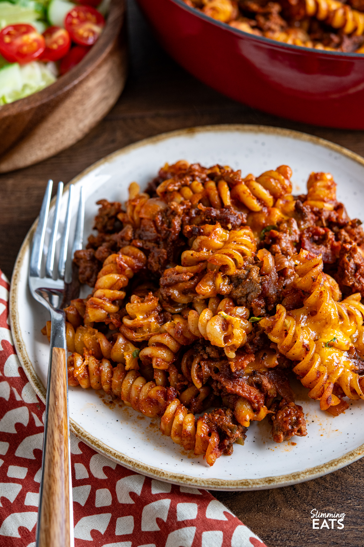 This BBQ Bacon Cheeseburger Pasta Bake is a hearty, flavour-packed family dinner with all the best cheeseburger flavours combined in one cheesy, comforting pasta dish. close up of BBQ Bacon Cheeseburger Pasta Bake on white plate with beige rim, fork place on side of plate.