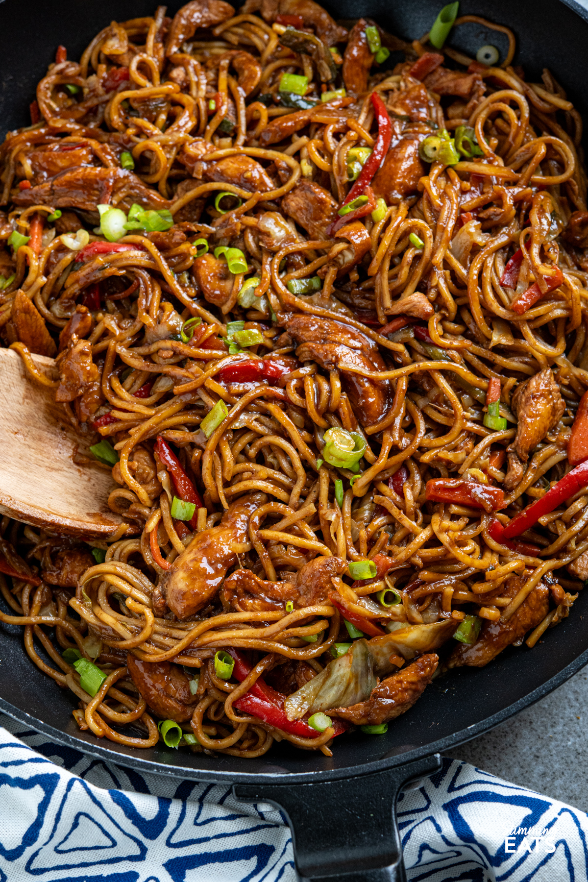 close up of Hoisin Chicken with noodle in black frying pan with wooden handle
