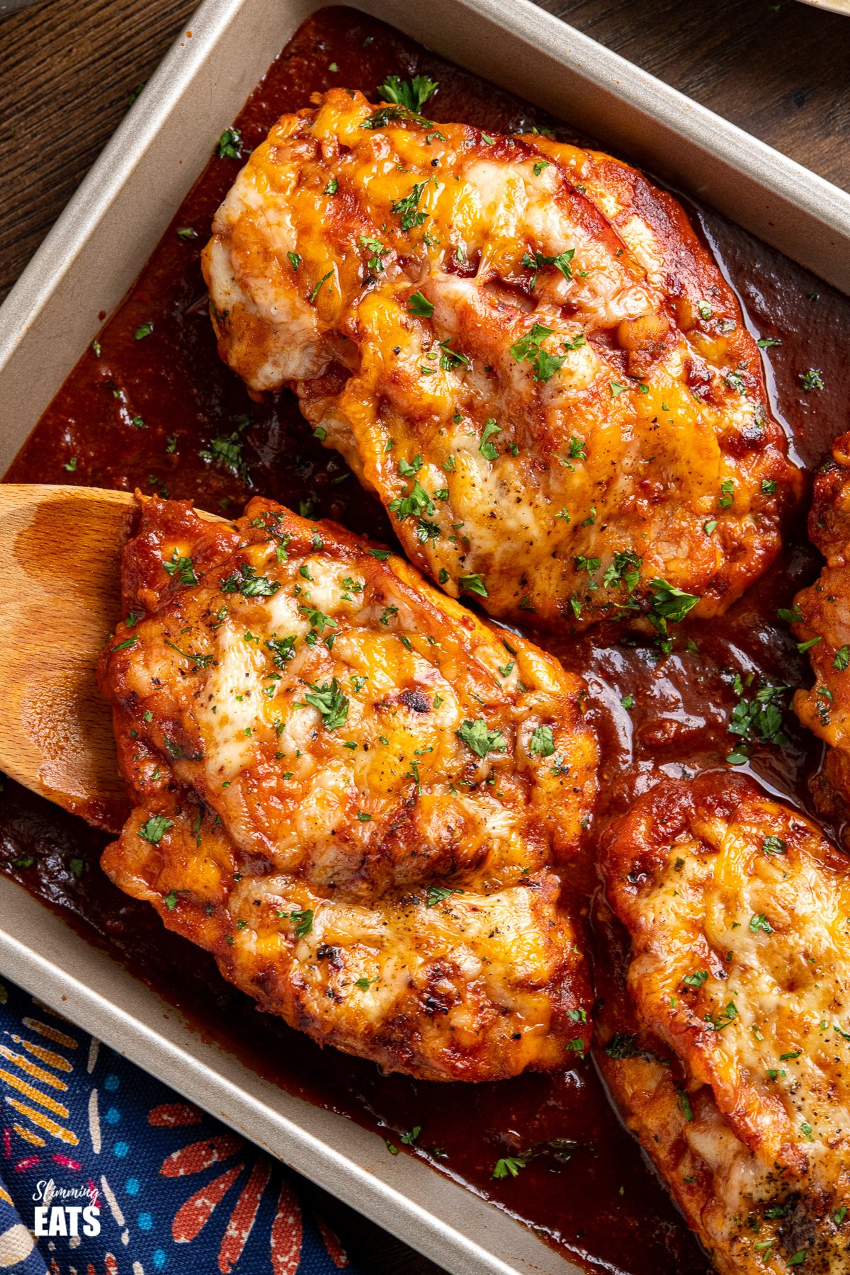 Hunters Chicken - tender chicken breasts in a delicious homemade barbecue sauce with slices of smoky bacon, all topped with cheese and baked until melted and golden. #chicken #barbecue #cheese #bacon #slimmingeats #weightwatchers #smartpoints close up of hunters chicken on baking tray with barbecue sauce