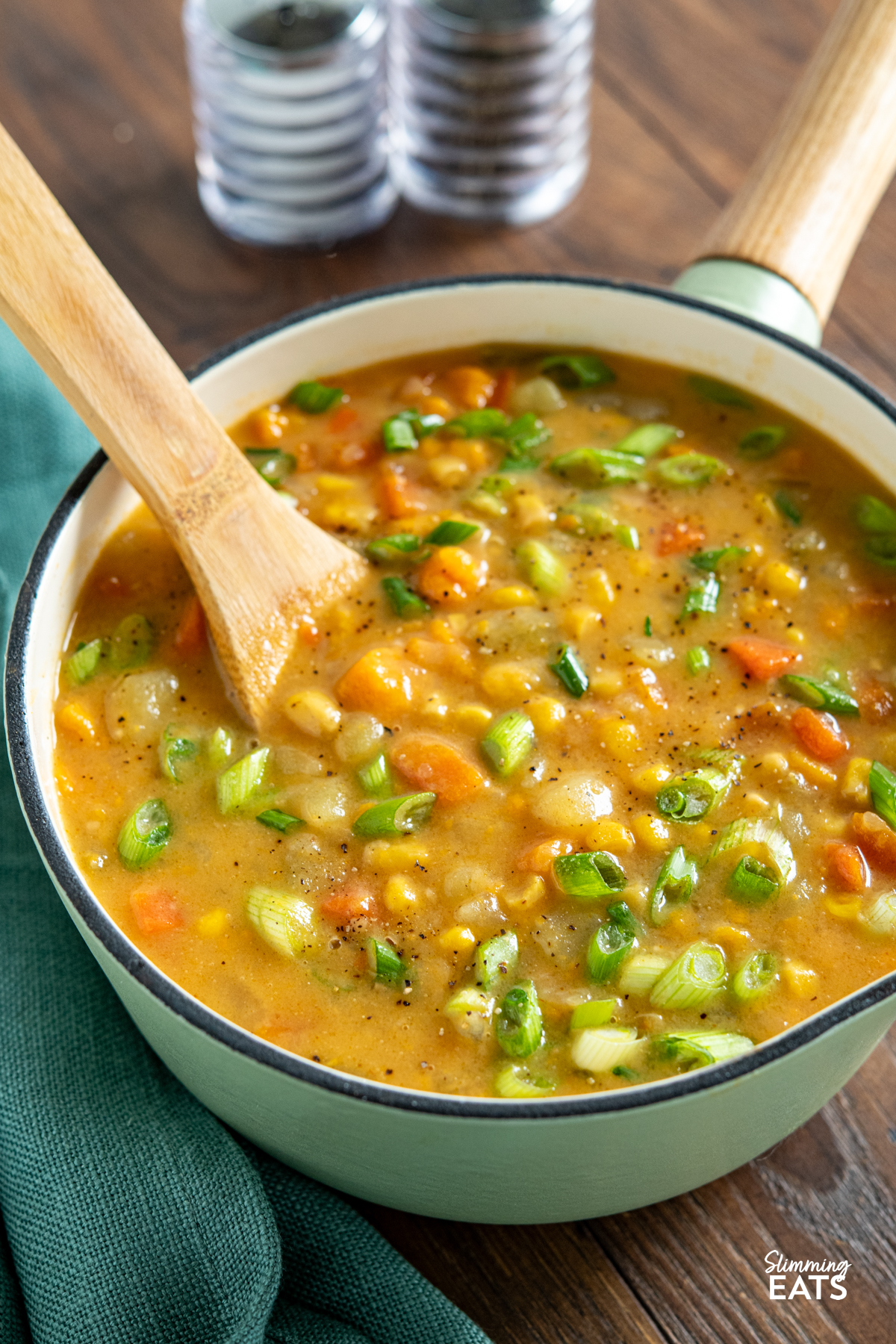 Creamy Vegan Vegetable Chowder - this chowder is delicious and packed with healthy vegetables. Perfect for those cold chilly fall and winter months. #vegan #glutenfree #dairyfree #slimmingeats #weightwatchers cast iron saucepan of vegan vegetable chowder with wooden spoon and salt and pepper shakers in background