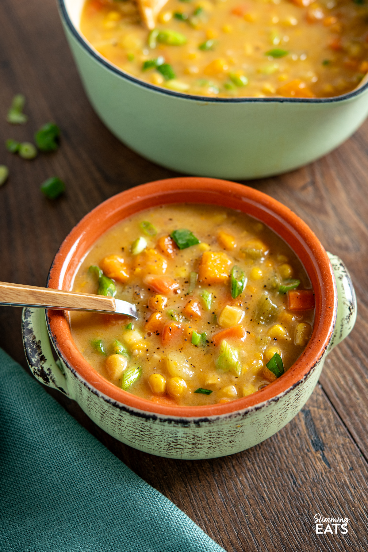 Creamy Vegan Vegetable Chowder - this chowder is delicious and packed with healthy vegetables. Perfect for those cold chilly fall and winter months. #vegan #glutenfree #dairyfree #slimmingeats #weightwatchers serving on creamy vegan vegetable chowder in ceramic bowl on wooden board, saucepan of soup in background