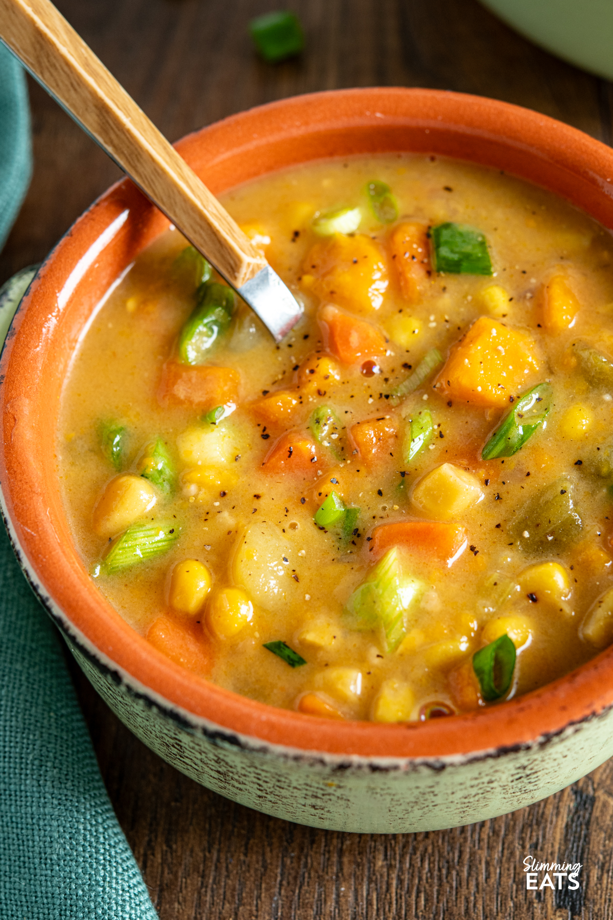 Creamy Vegan Vegetable Chowder - this chowder is delicious and packed with healthy vegetables. Perfect for those cold chilly fall and winter months. #vegan #glutenfree #dairyfree #slimmingeats #weightwatchers close up of bowl of vegan vegetable chowder on wooden board with spoon