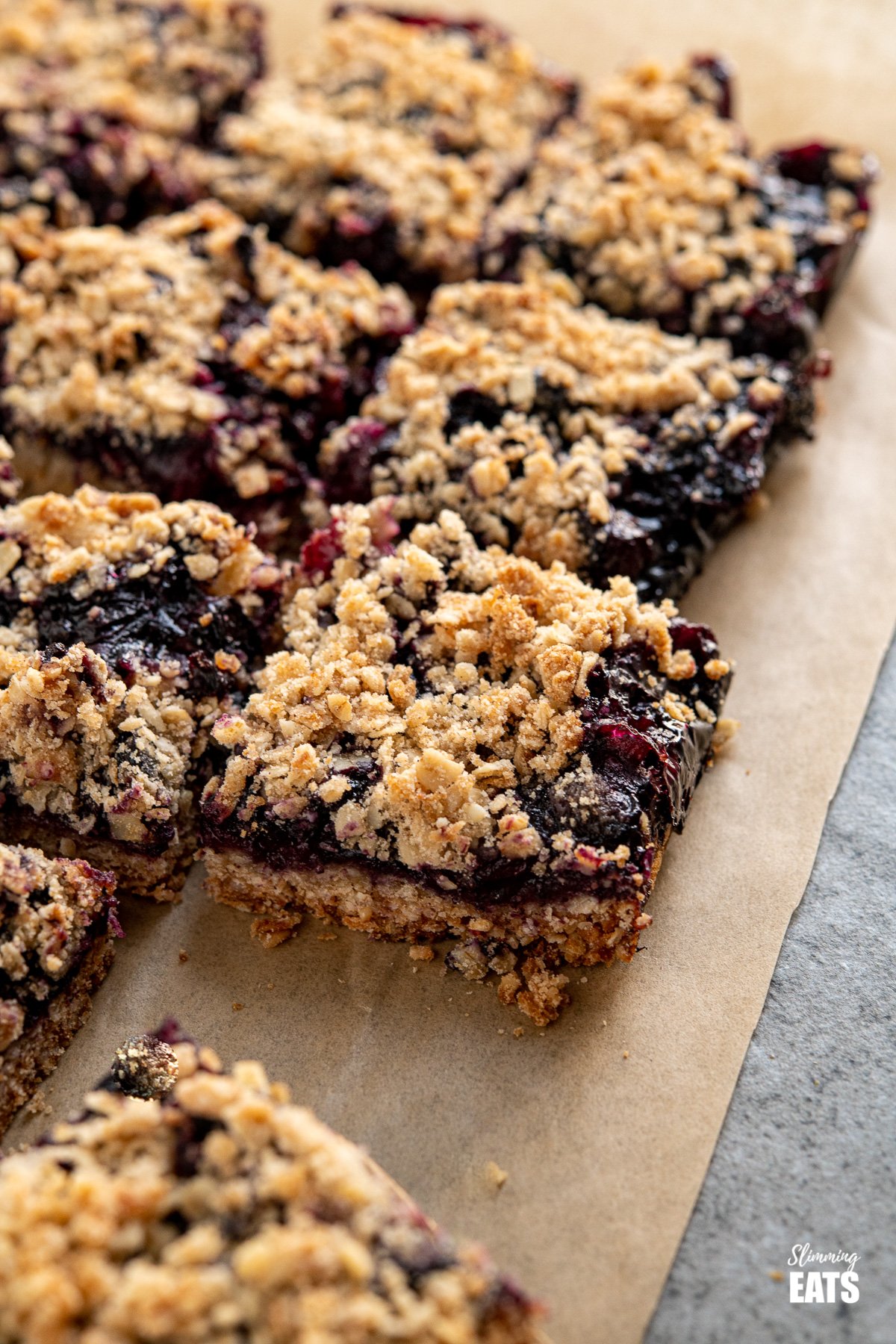 portioned up blueberry oat crumble bars on parchment paper