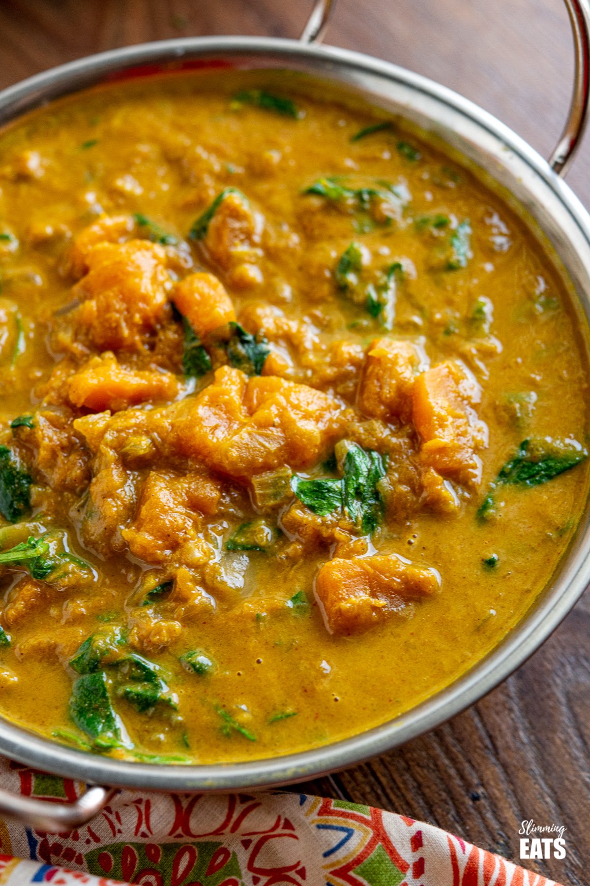Easy Butternut Squash Curry with Spinach - a simple delicious vegan curry with chunks of butternut squash and a creamy coconut curry sauce. It's a perfect recipe for the whole family. #vegan #vegetarian #butternutsquash #curry #coconut #slimmingeats #weightwatchers close up of Easy Butternut Squash Curry with Spinach in metal dish