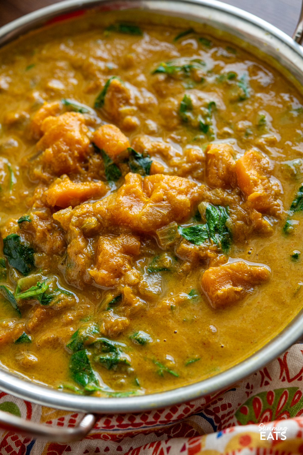 Easy Butternut Squash Curry with Spinach - a simple delicious vegan curry with chunks of butternut squash and a creamy coconut curry sauce. It's a perfect recipe for the whole family. #vegan #vegetarian #butternutsquash #curry #coconut #slimmingeats #weightwatchers close up of Easy Butternut Squash Curry with Spinach in metal dish