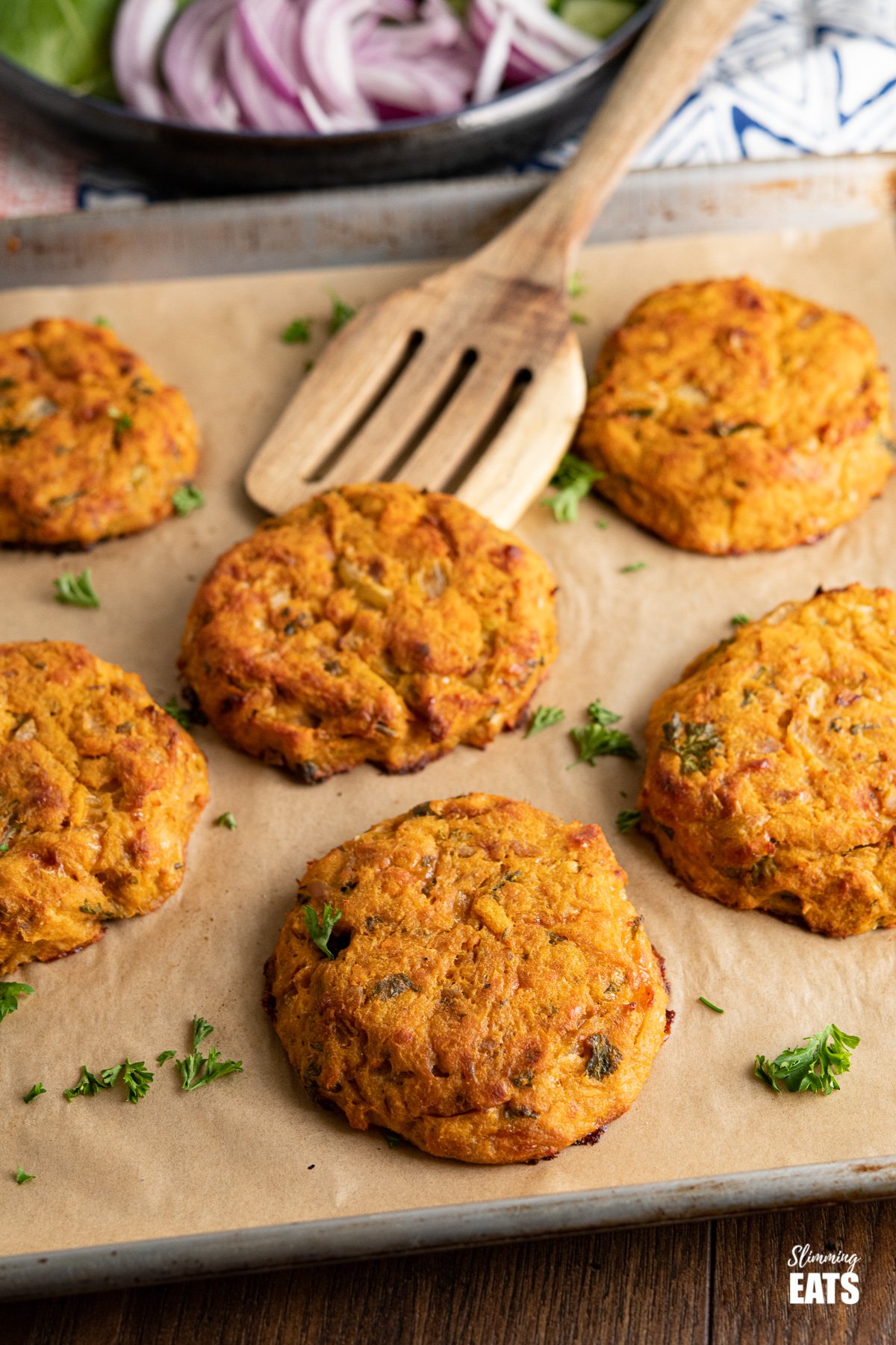 Tuna Sweet Potato Cheddar Patties on parchment lined baking tray with wooden spatula